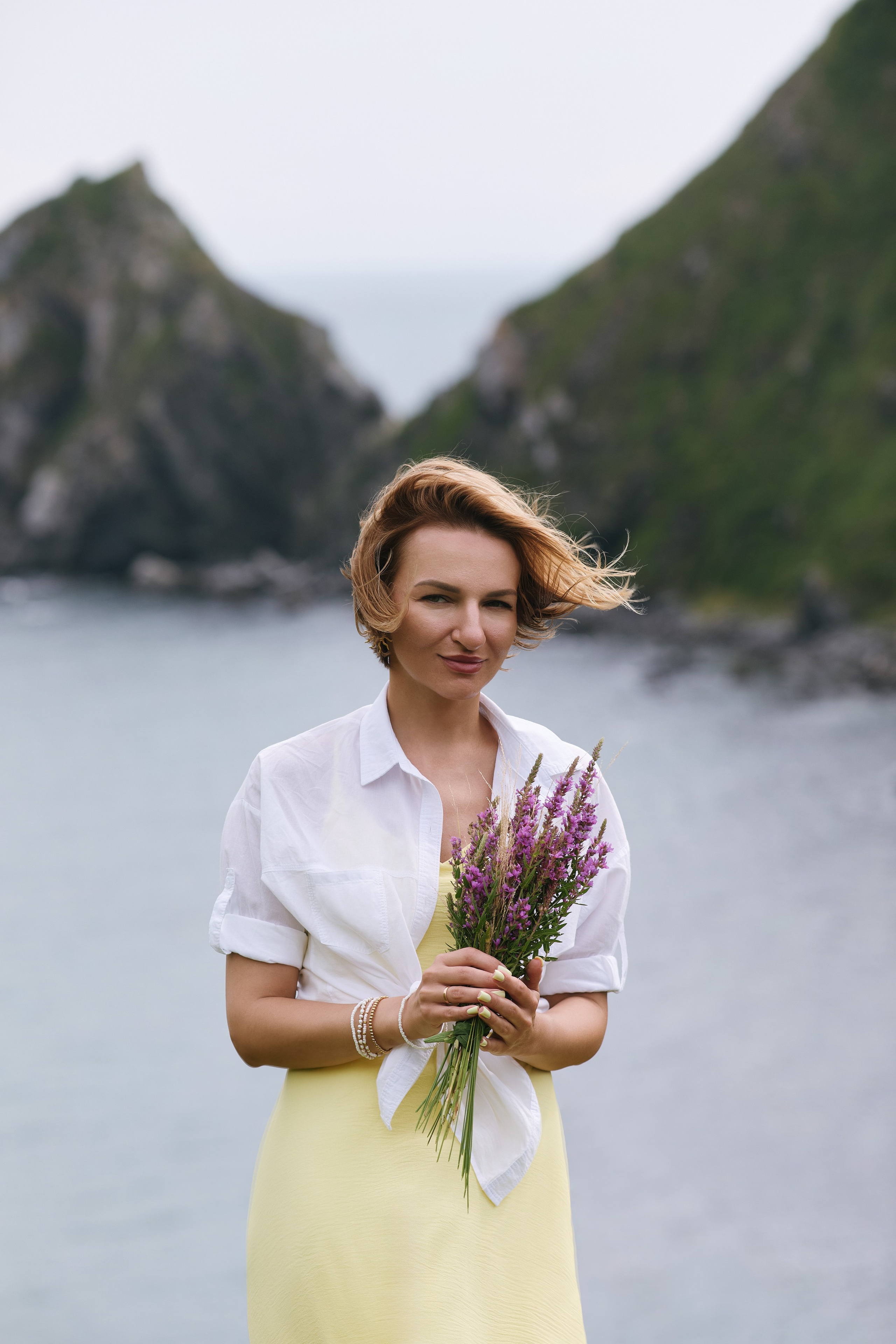 Идея для съёмки на фоне моря и скал с цветами в руках