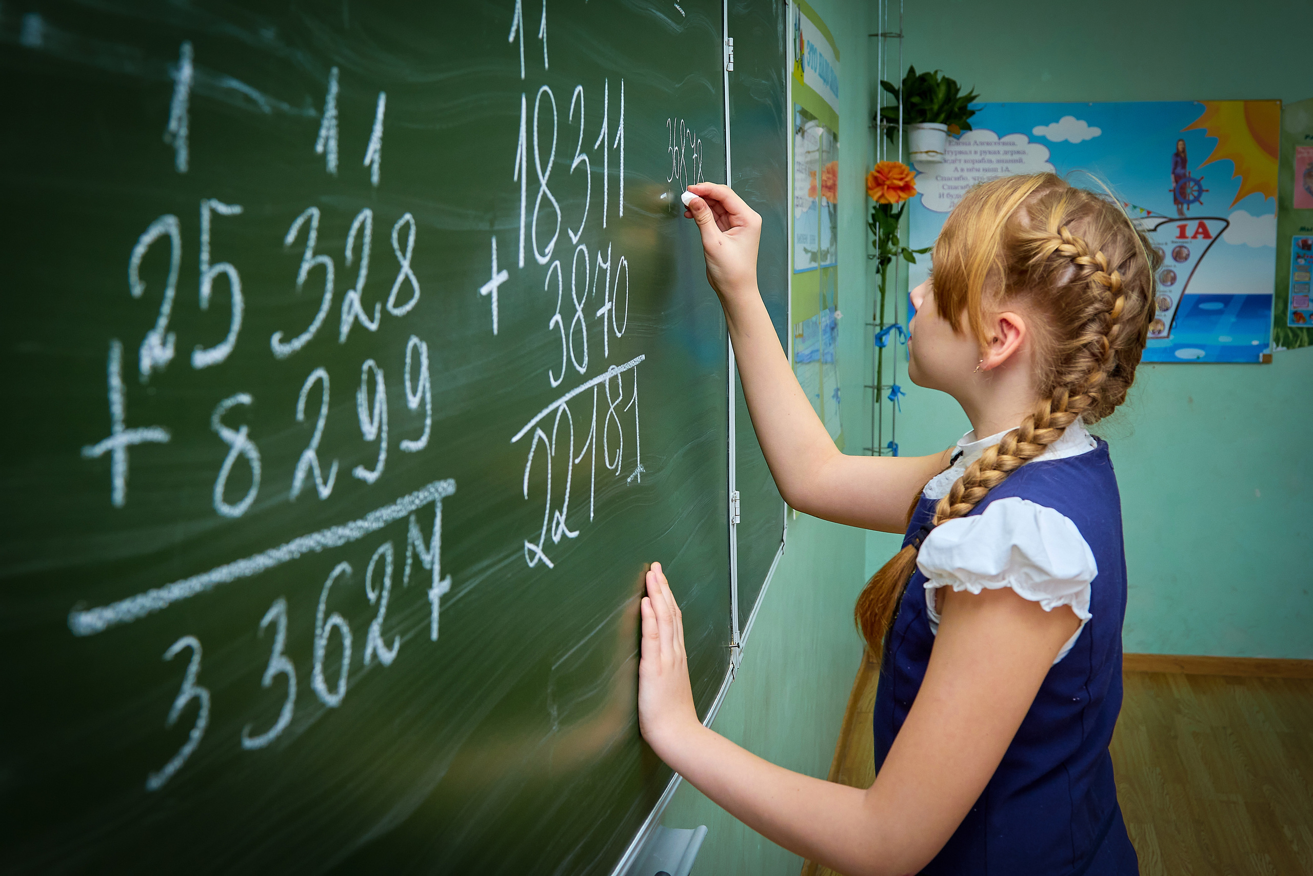 Девочка школьница пишет на доске