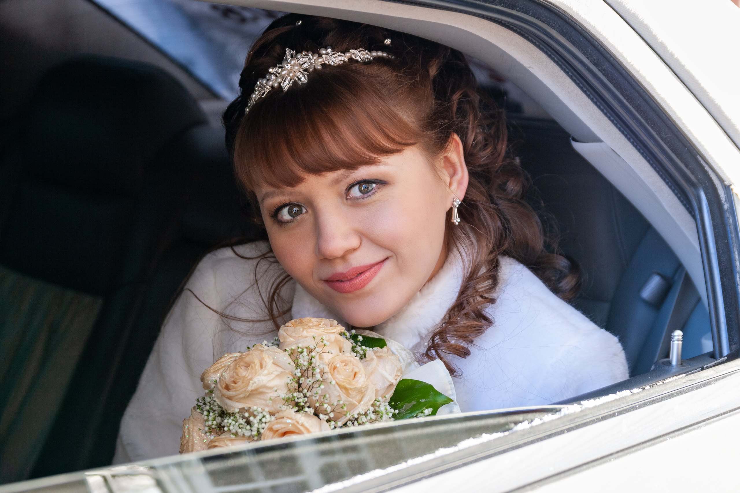 Невеста выглядывает из окна с букетом в руке