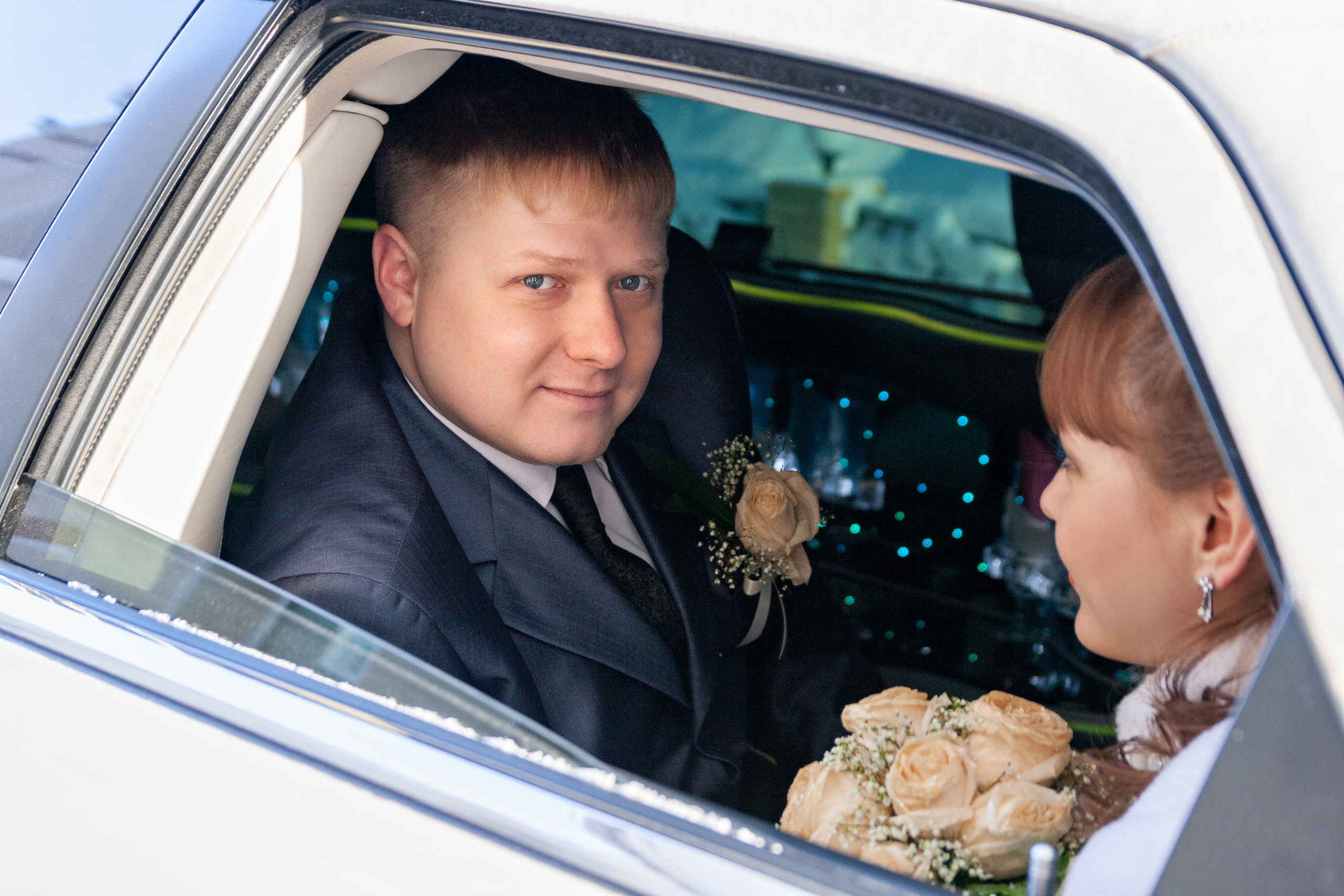 Жених с невестой в окне автомобиля