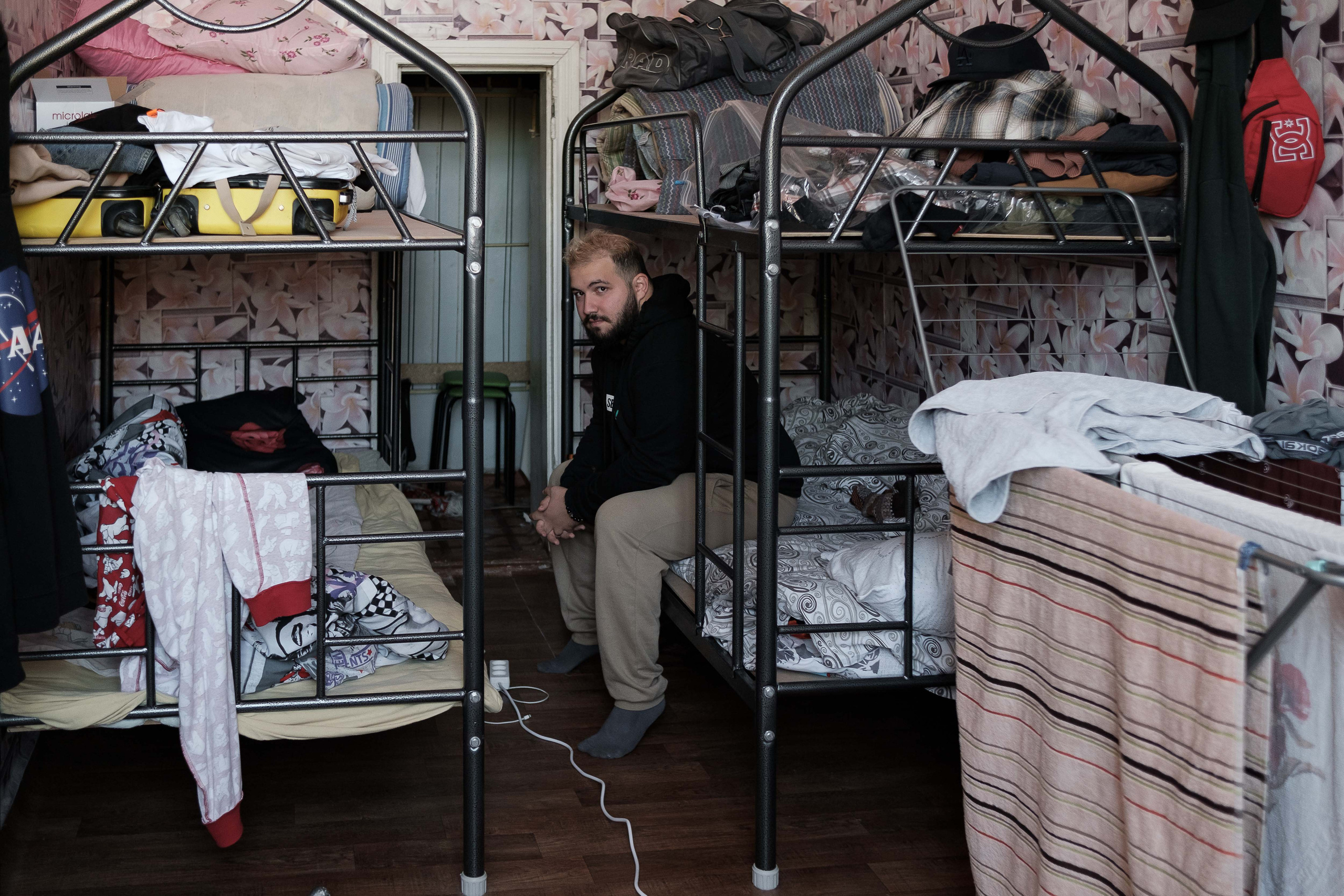 Anton from Saratov is in his room in Uralsk, where they live with friends. Anton arrived in Uralsk from Saratov on business three days before the start of the partial mobilization and, as he jokes, as he knew and arrived in advance. Later it became clear that it would not be possible to return home. A few days later, Anton met his friends from Saratov and quietly transported things from Russia via taxi. Now the whole company of 5 people lives in a small apartment with bunk beds in Uralsk. In Russia, Anton was engaged in massage and music. Now he performs in a local bar in Uralsk, and later plans to open his own massage room and continue to stay in Kazakhstan to develop his business.