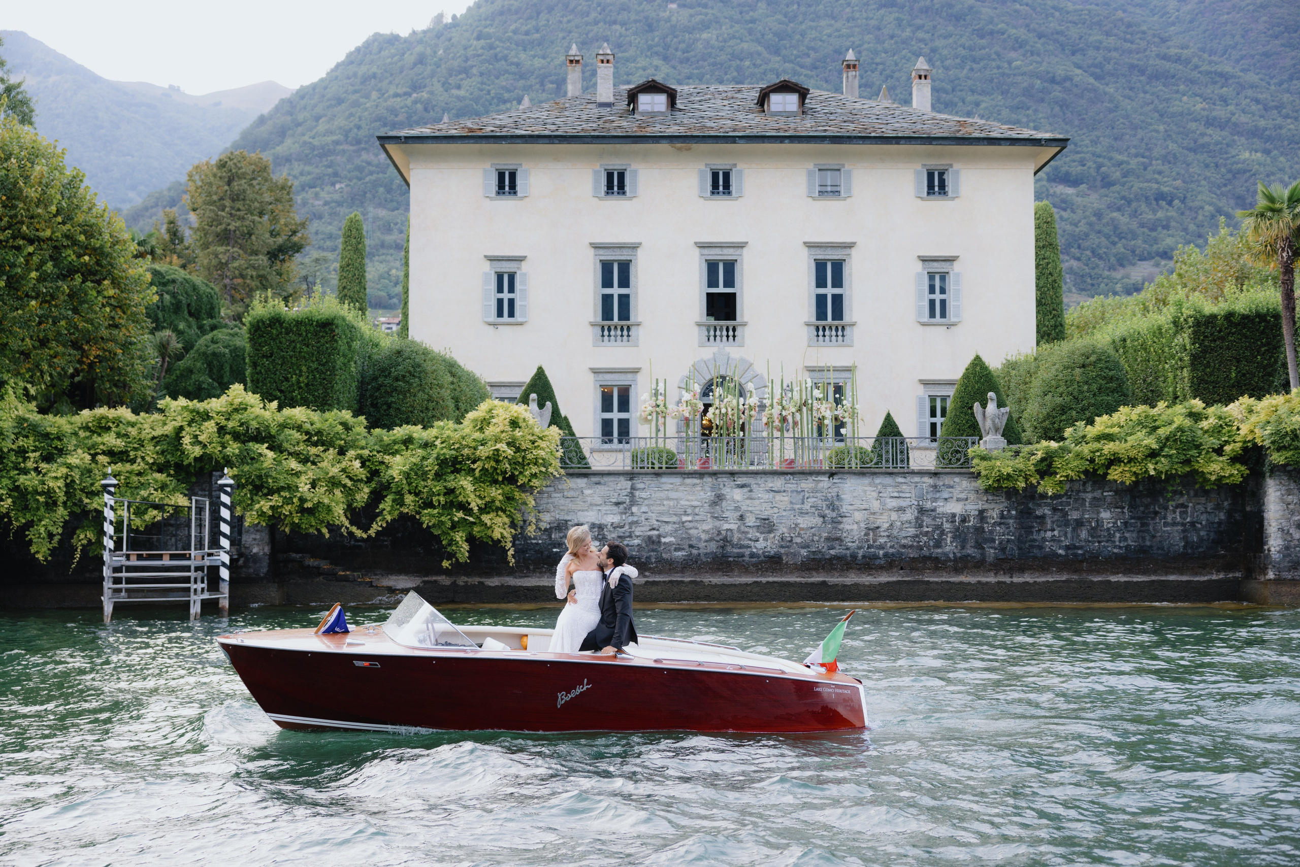 Newlyweds in a wooden boat on Lake Como surrounded by mountains