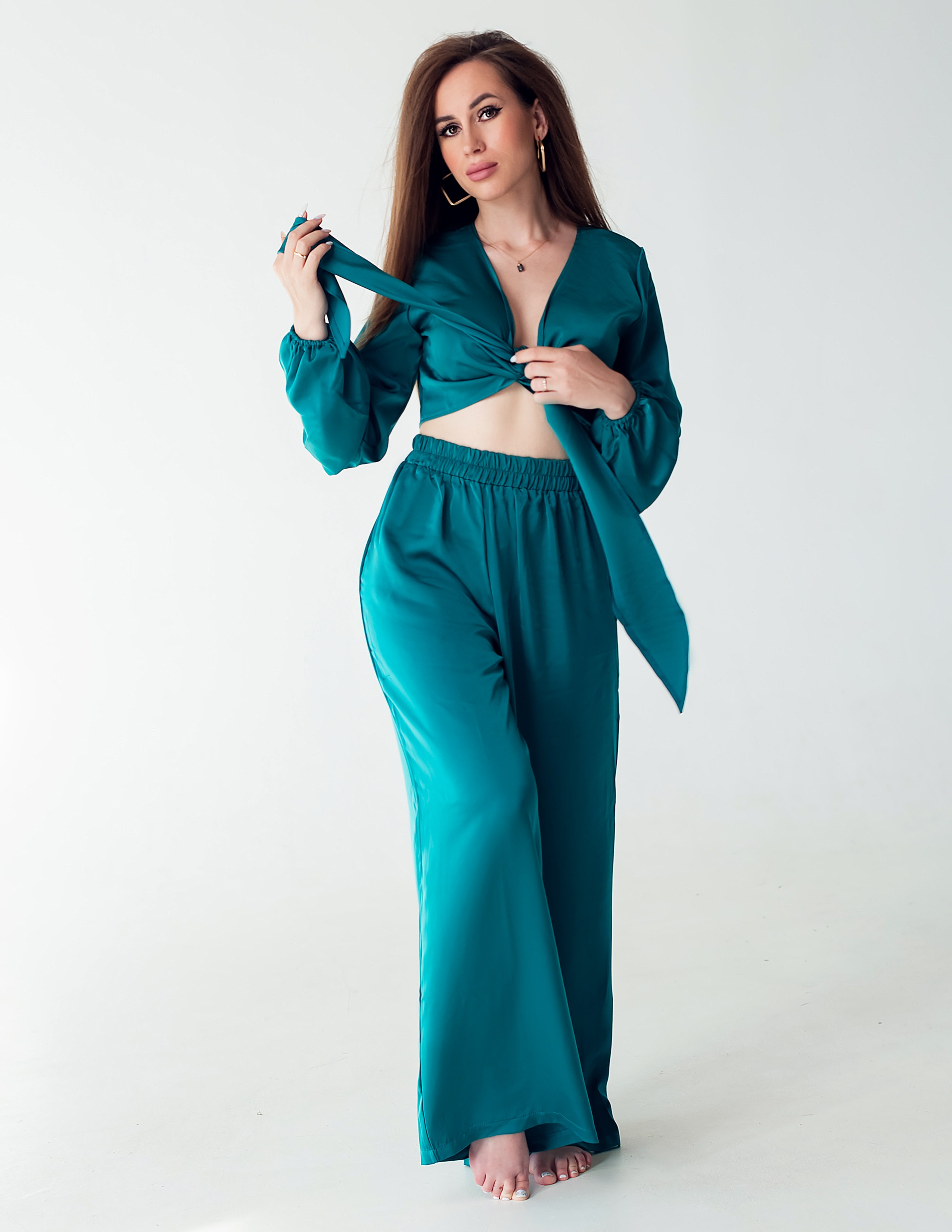 Красивая девушка в изумрудном костюме пижамного стиля, фотоссесия на циклораме в студии.