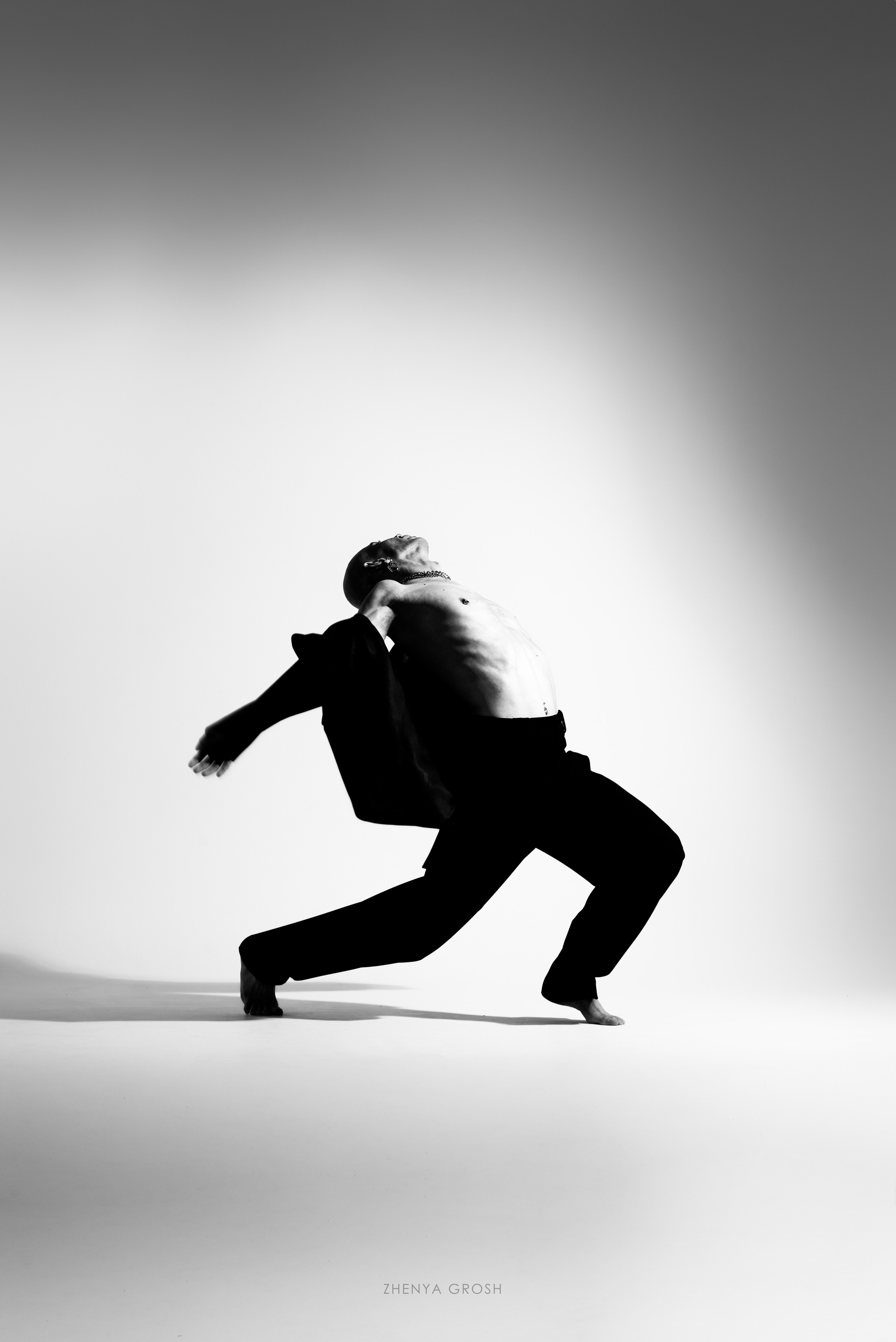мужчина в черных брюках и пиджаке танцует на белом фоне