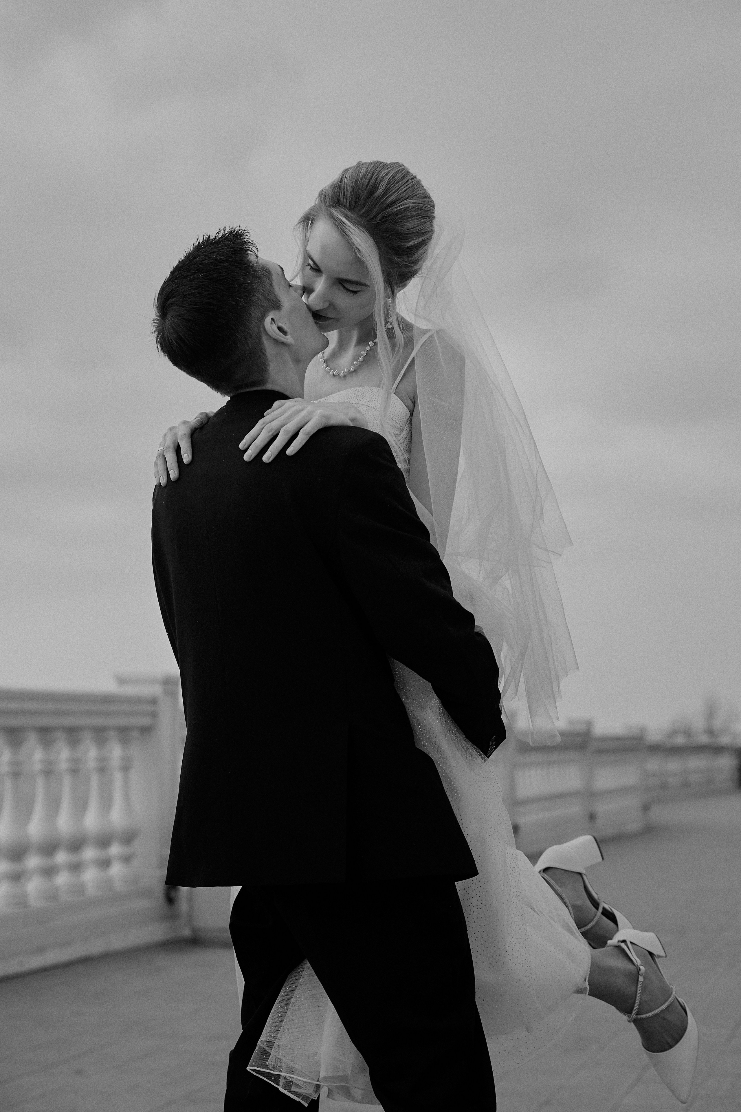 Черно белое фото со свадебной фотосессии в Анапе, жених держит невесту на руках и целует