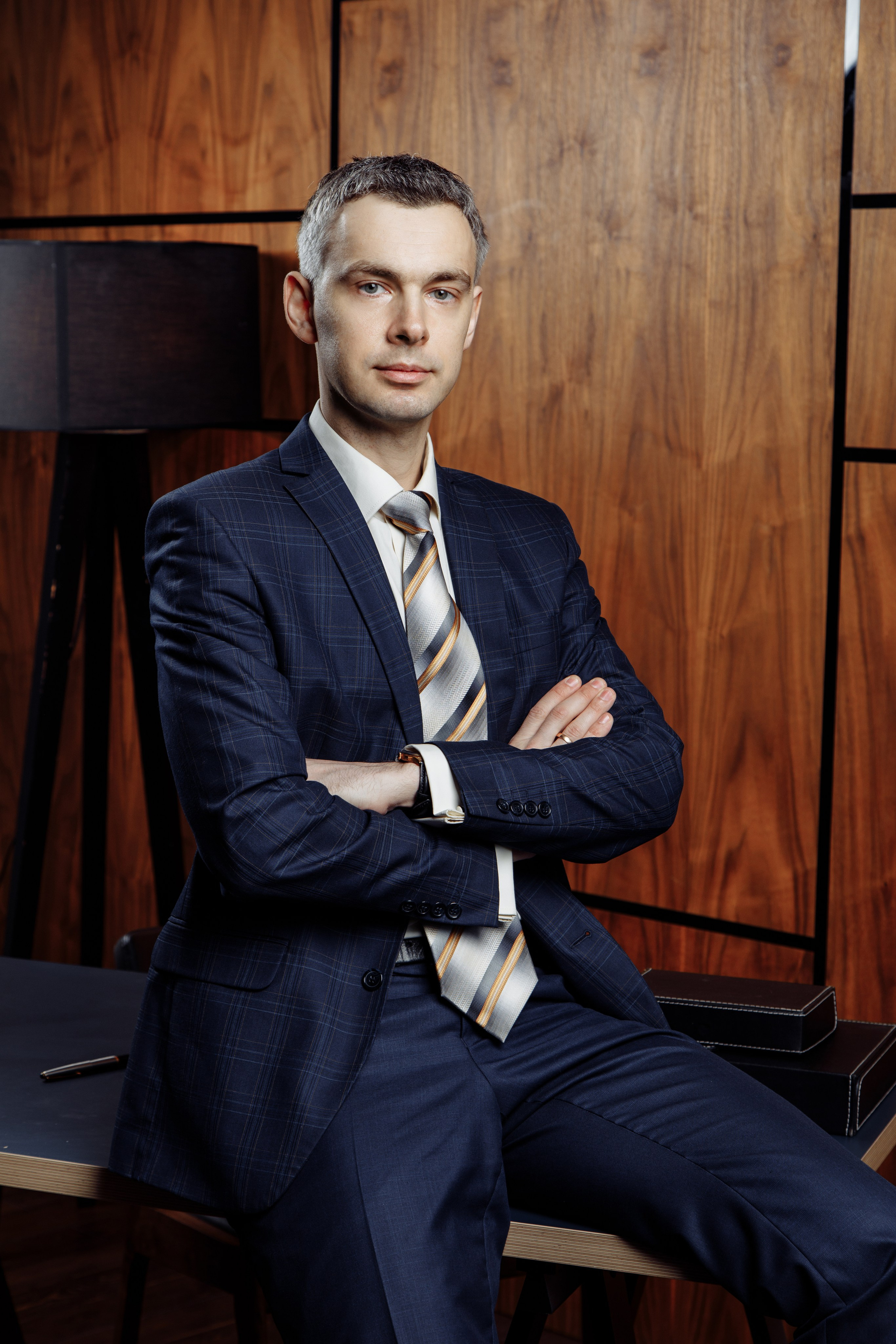 Теплый деловой портрет мужчины на фоне натуральной деревянной стены.