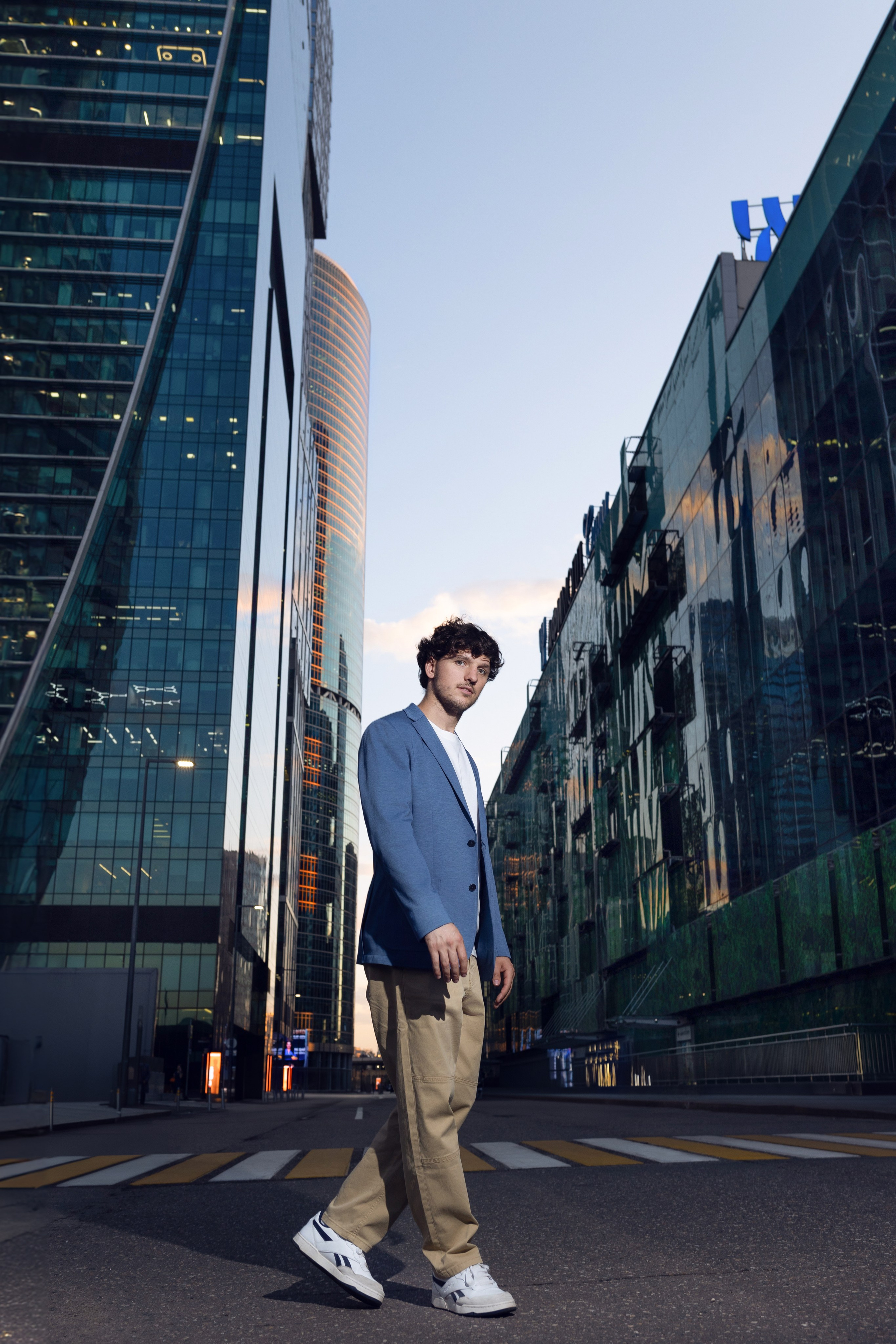 Мужчина в полный рост позирует на фоне небоскребов Москва-Сити.