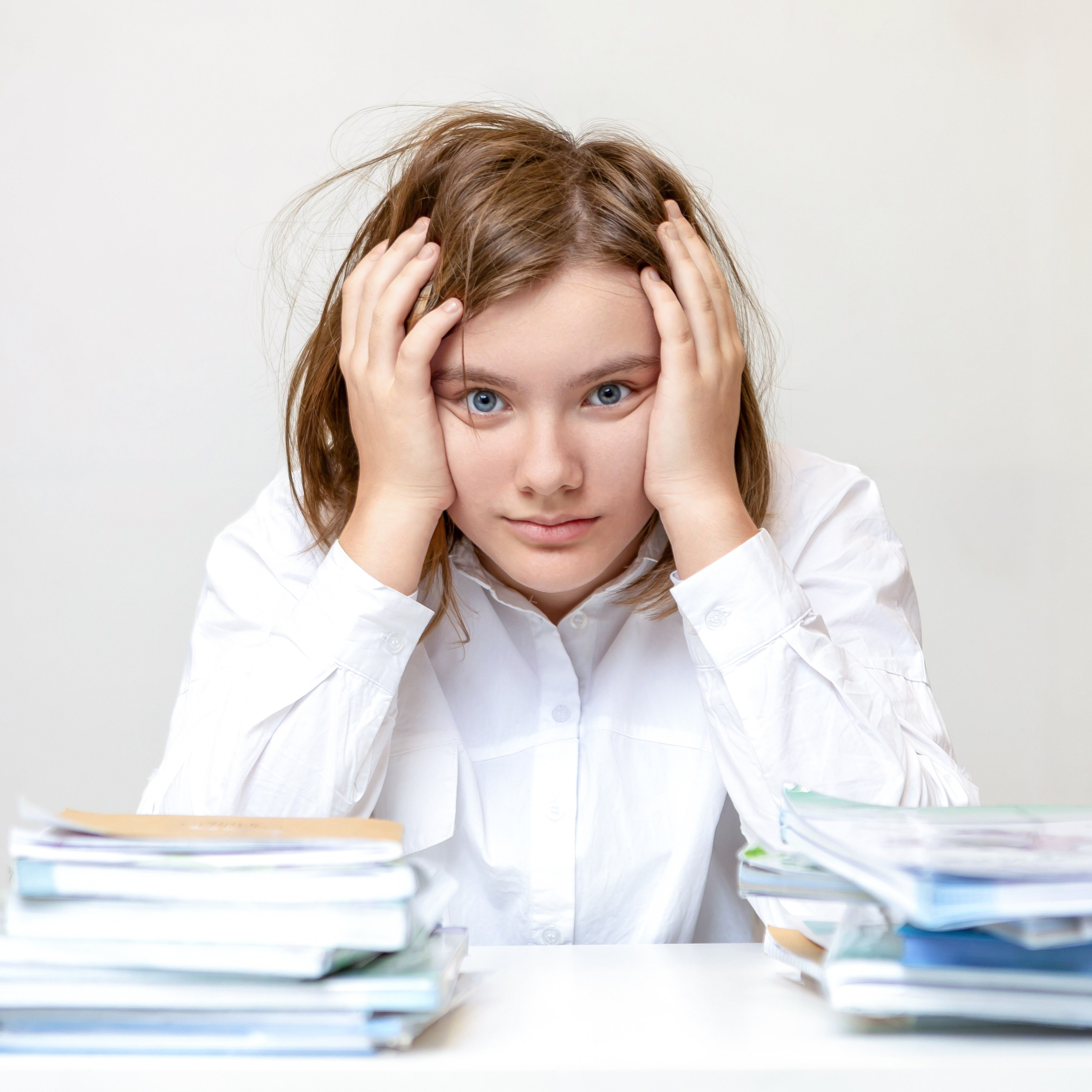 Девочка держит голову руками за партой, задумчивый портрет