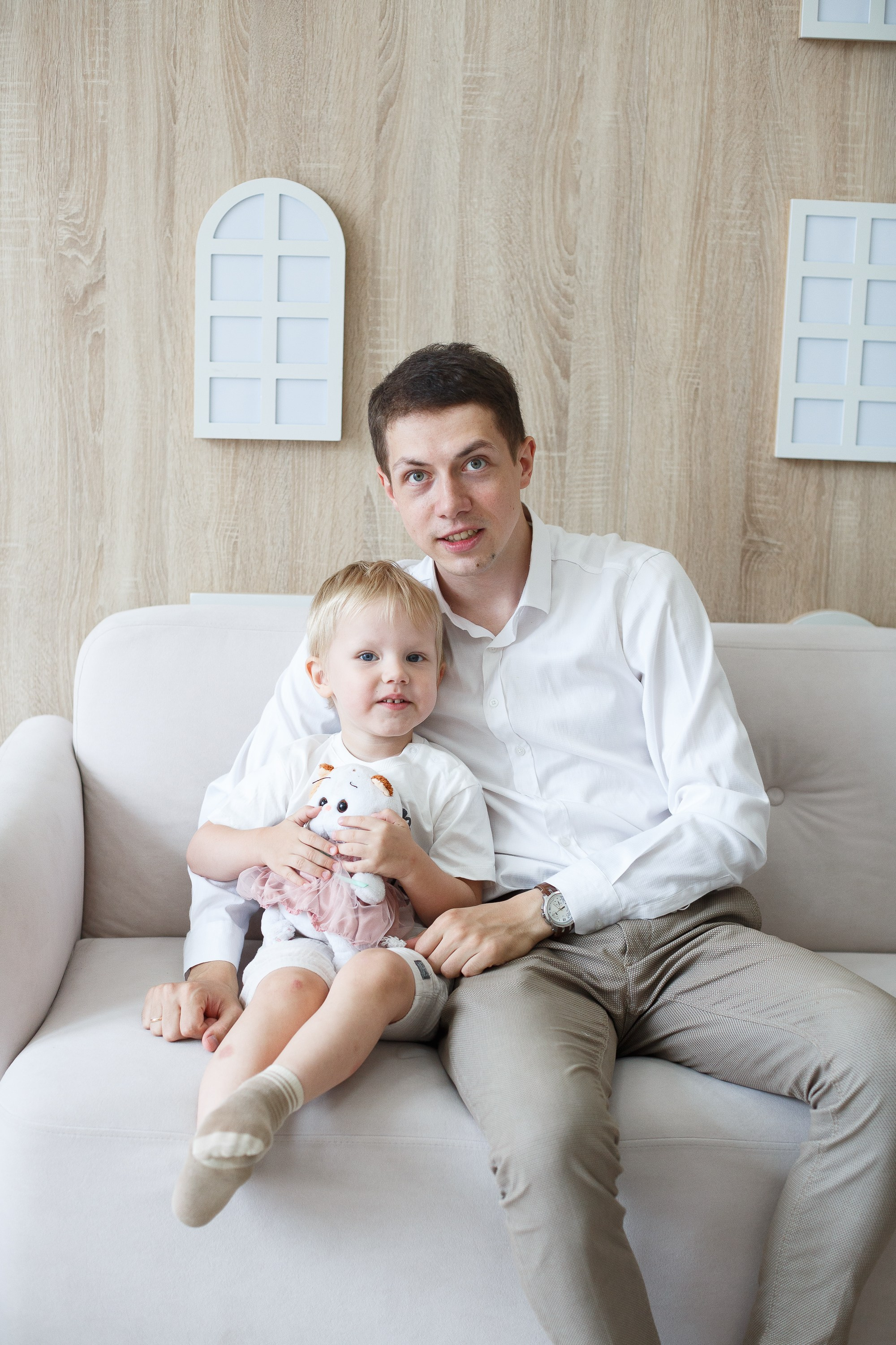 Семейная фотосессия в студии. Папа и сын сидят на диване.