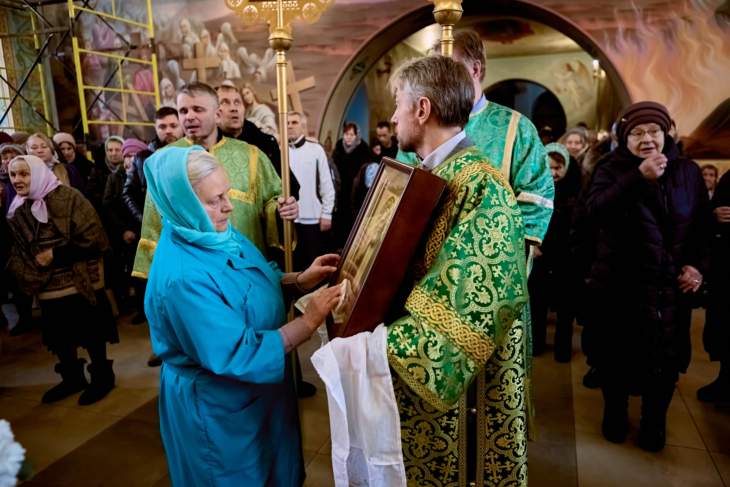 Женщина протирает праздничную Икону Преподобного Серафима Саровского