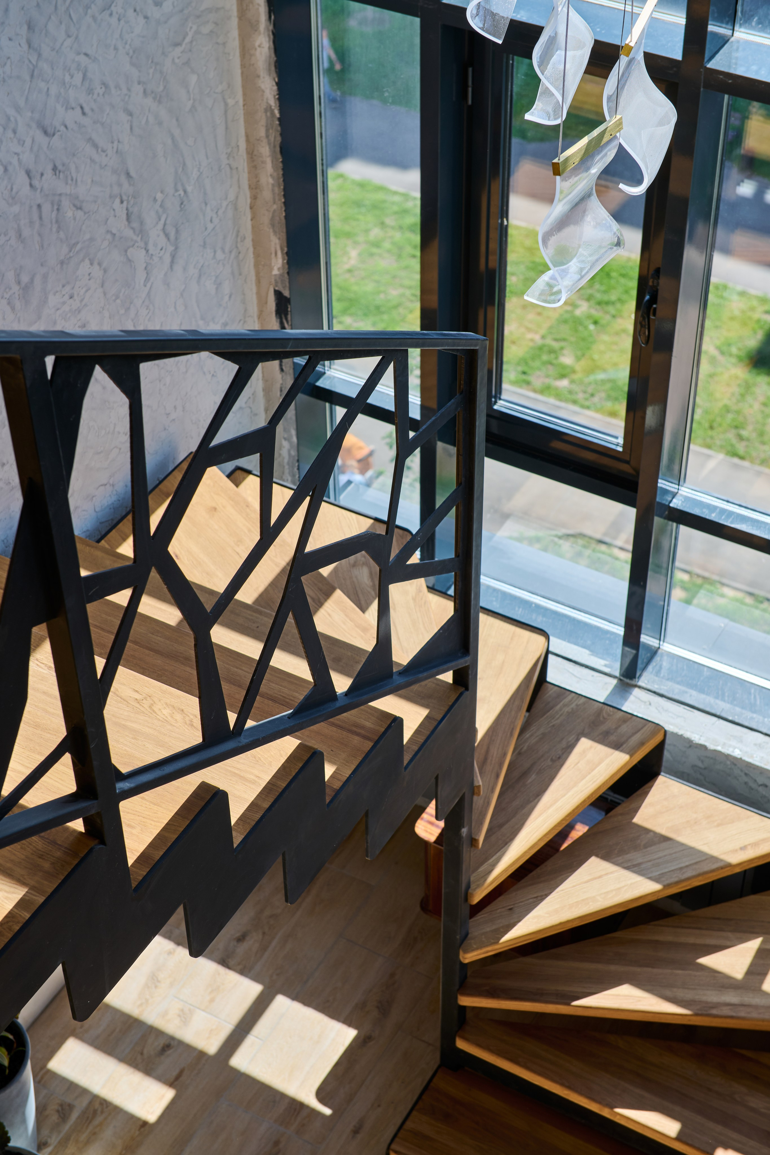 Лестница на второй уровень: чёрные перила, графичные тени, окно