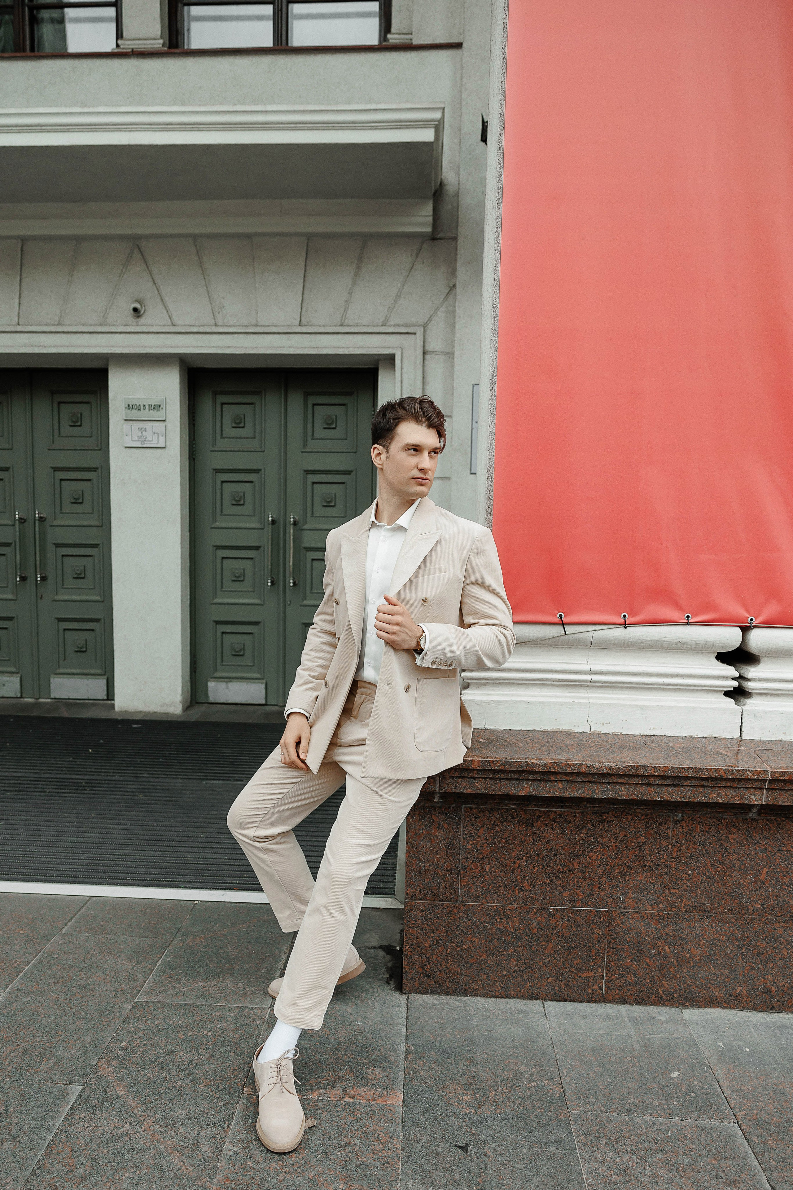 Жених сидит на фоне красного флага возле Театра драмы имени Кольцова в Воронеже