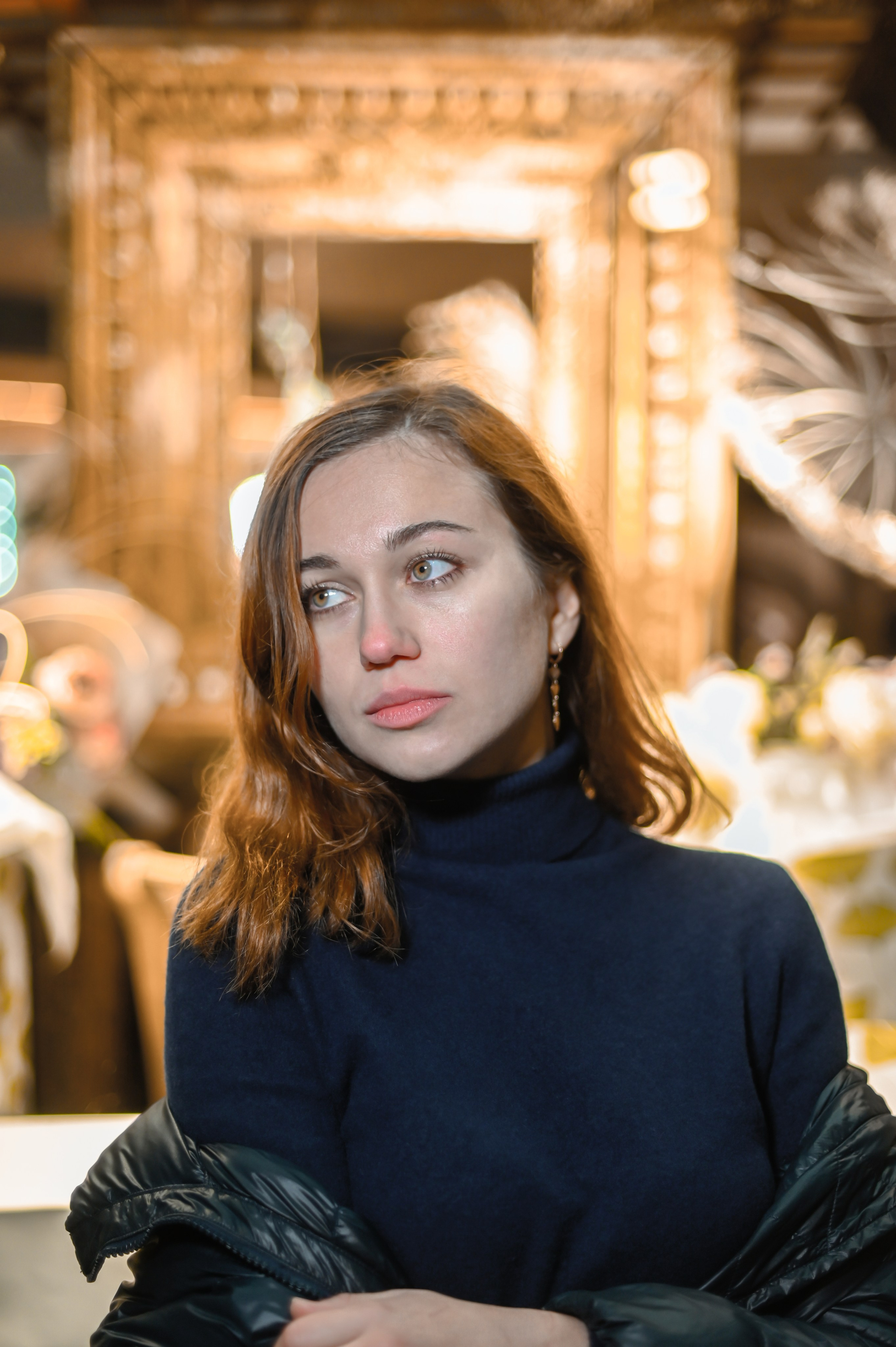 Портрет девушки с волнистыми рыжими волосами и элегантными серьгами, снятый в стильном помещении в Москве.