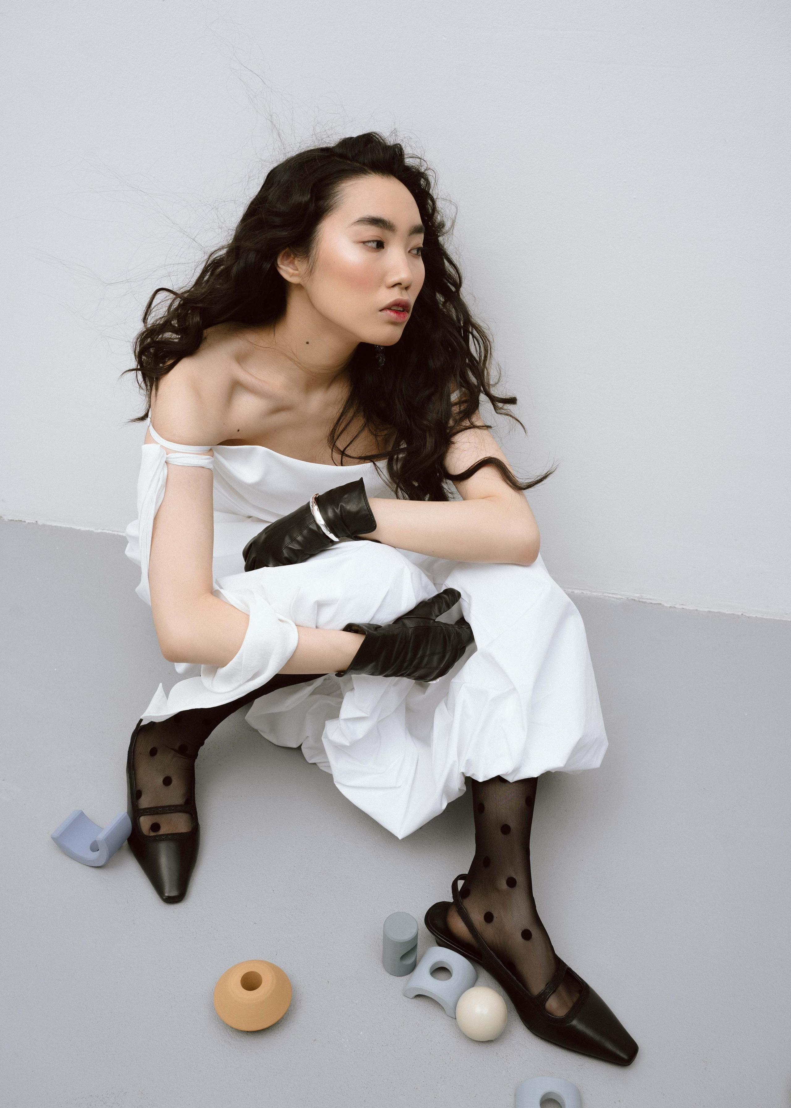 Азиатская модель сидит на полу в фотостудии на творческой съемке