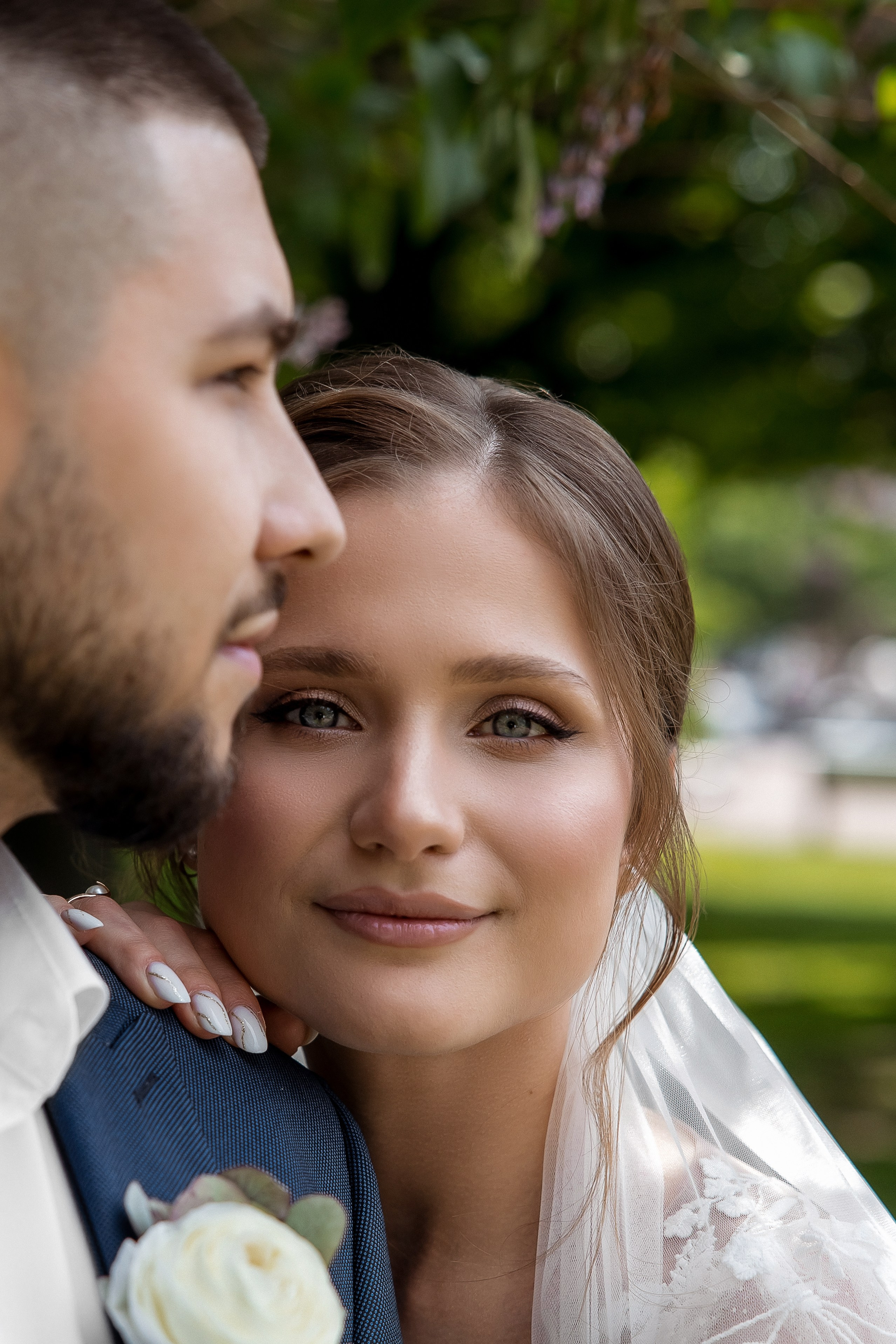 Красивый свадебный портрет молодой пары на фоне зелени