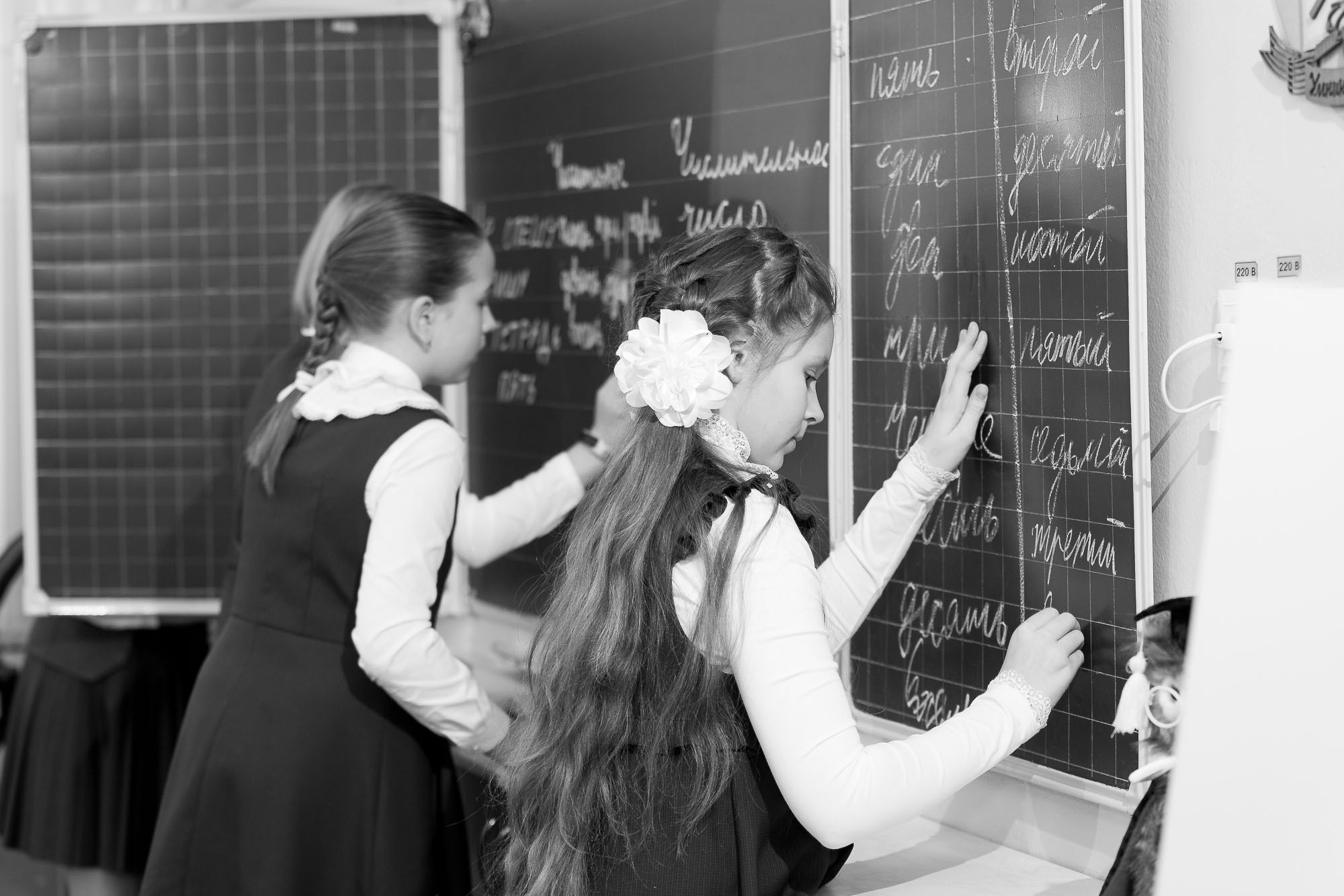 Две ученицы 4 класса пишут мелом на классной доске.