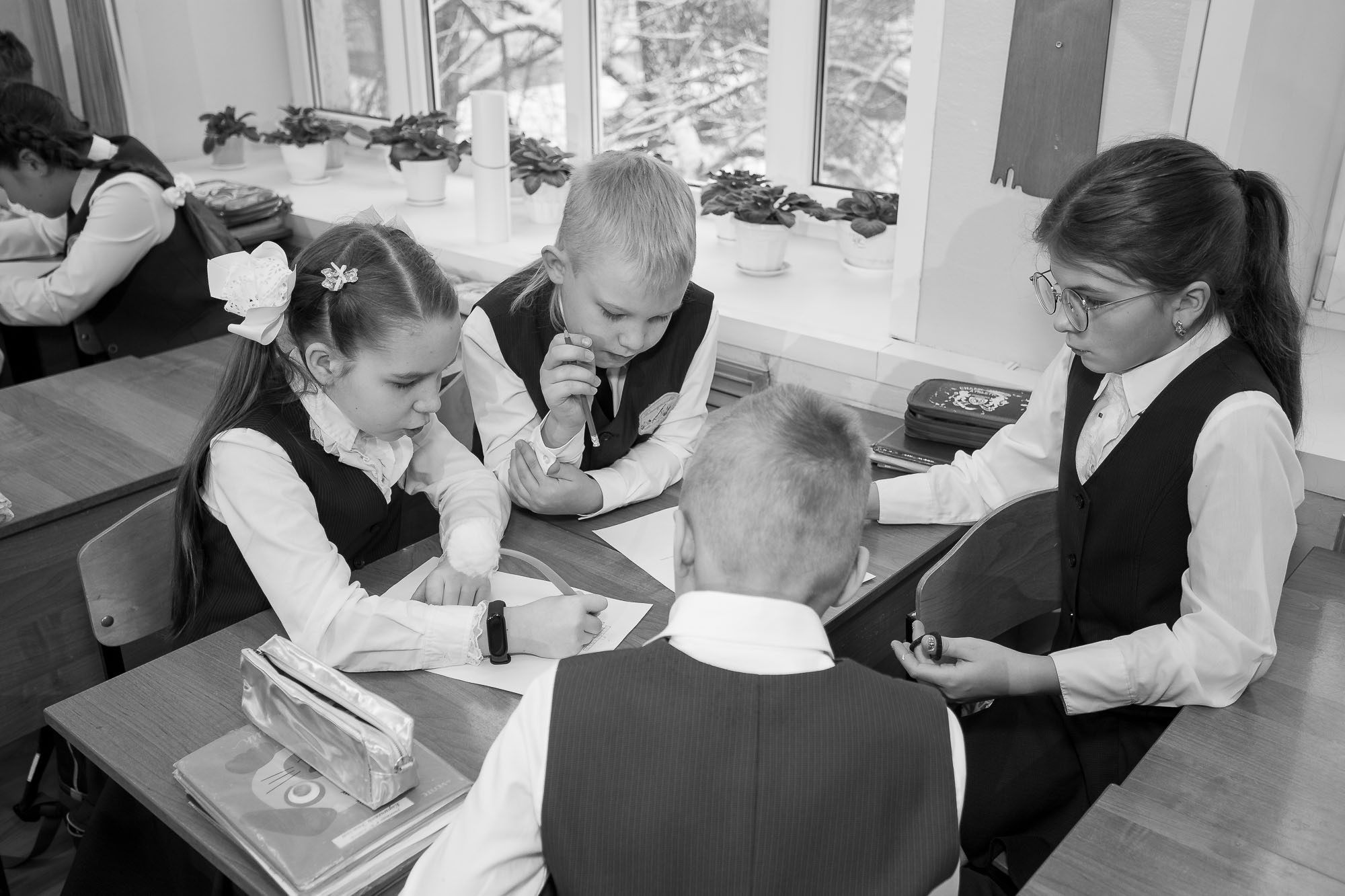 Работа в группе четырех выпускников начальной школы за партой. Вид сверху.