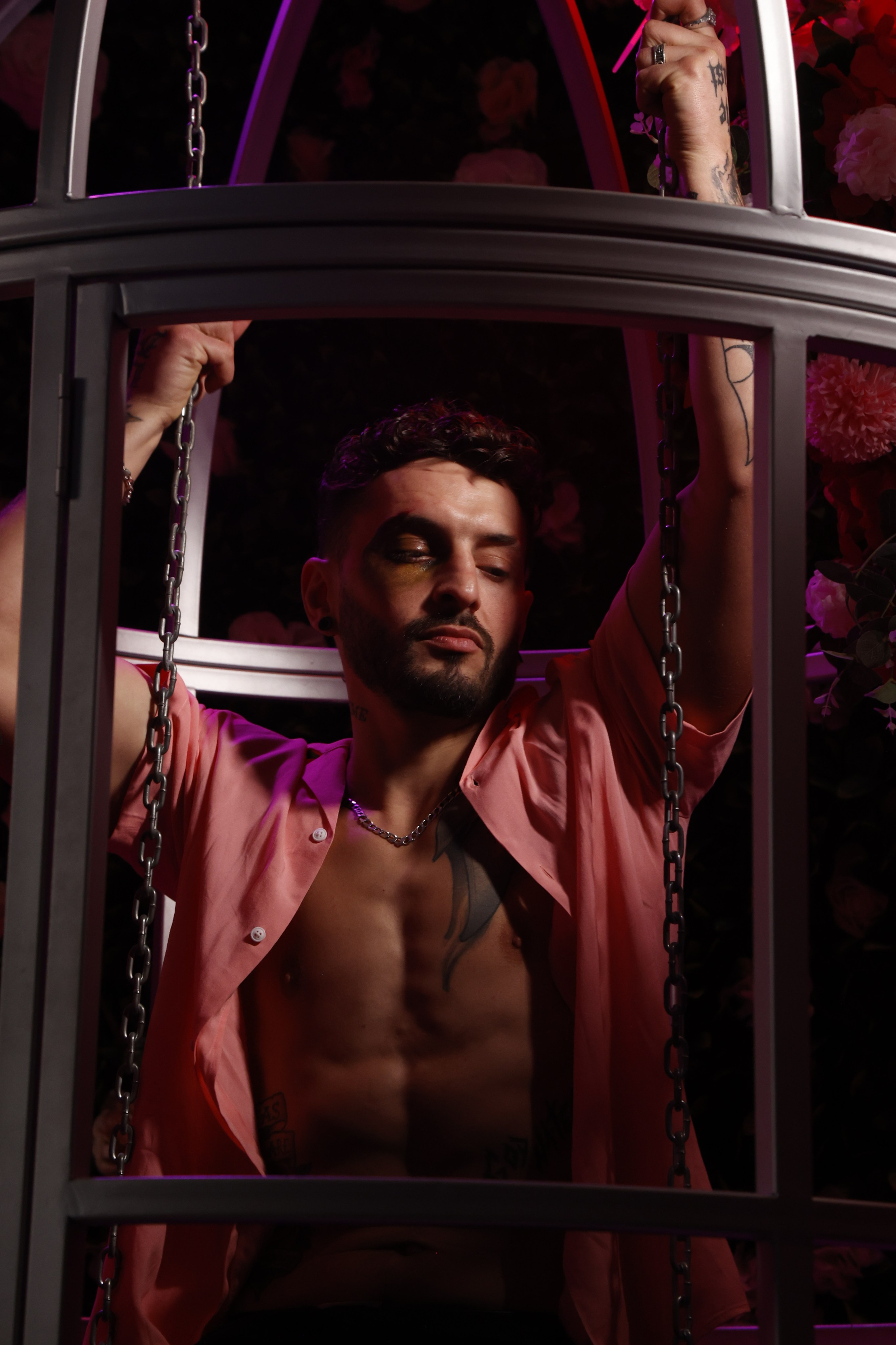 Male model in a glitter cage surrounded by pink haze, surreal fashion photography