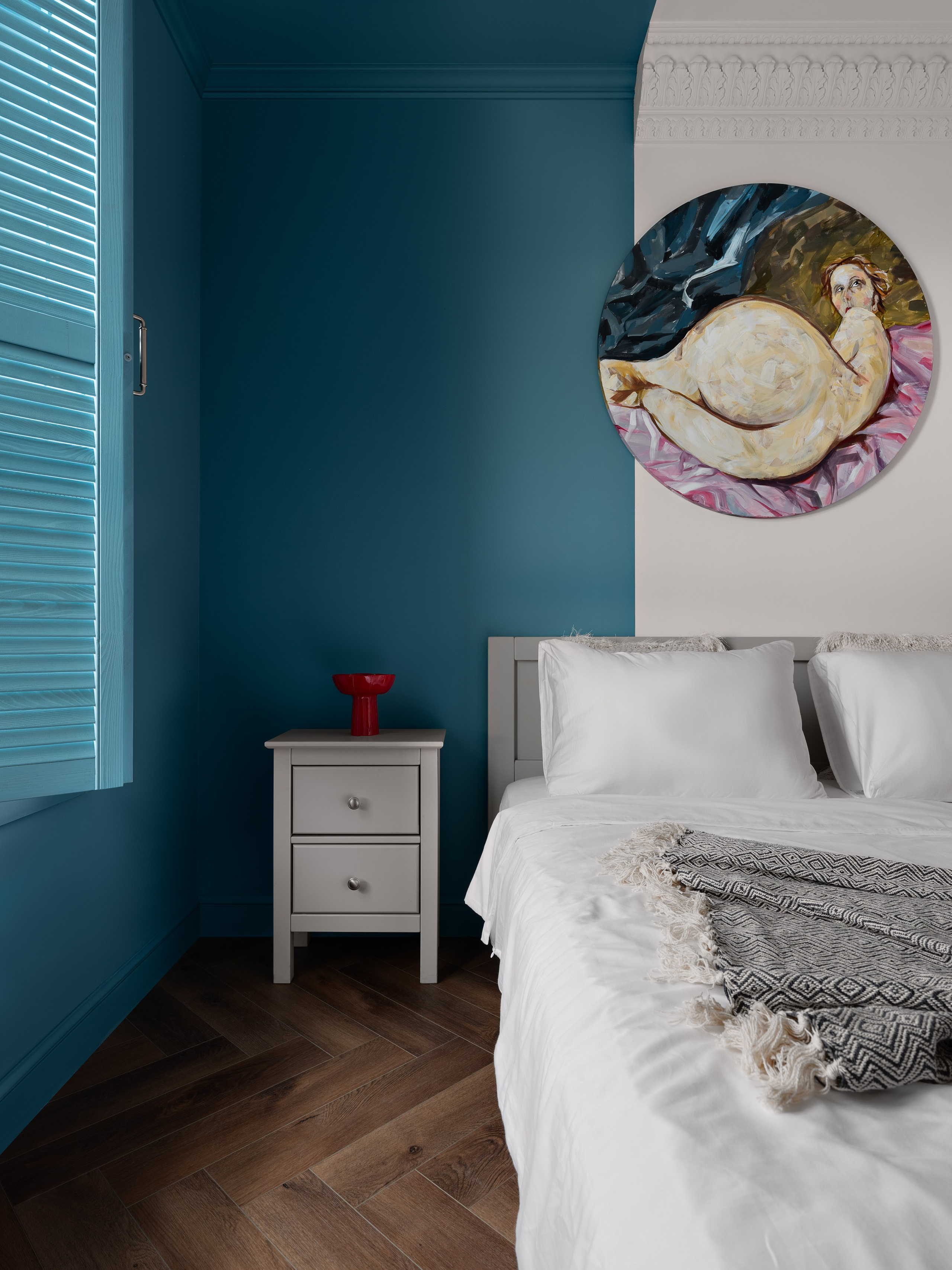 Яркая спальня с акцентной стеной глубокого синего цвета, паркетным полом «ёлочкой», белой кроватью и прикроватной тумбой с красным аксессуаром. Дизайнер Антон Логинов, стилист Алёна Мощенская, фотограф Сергей Денисенко отразили стиль и уют.