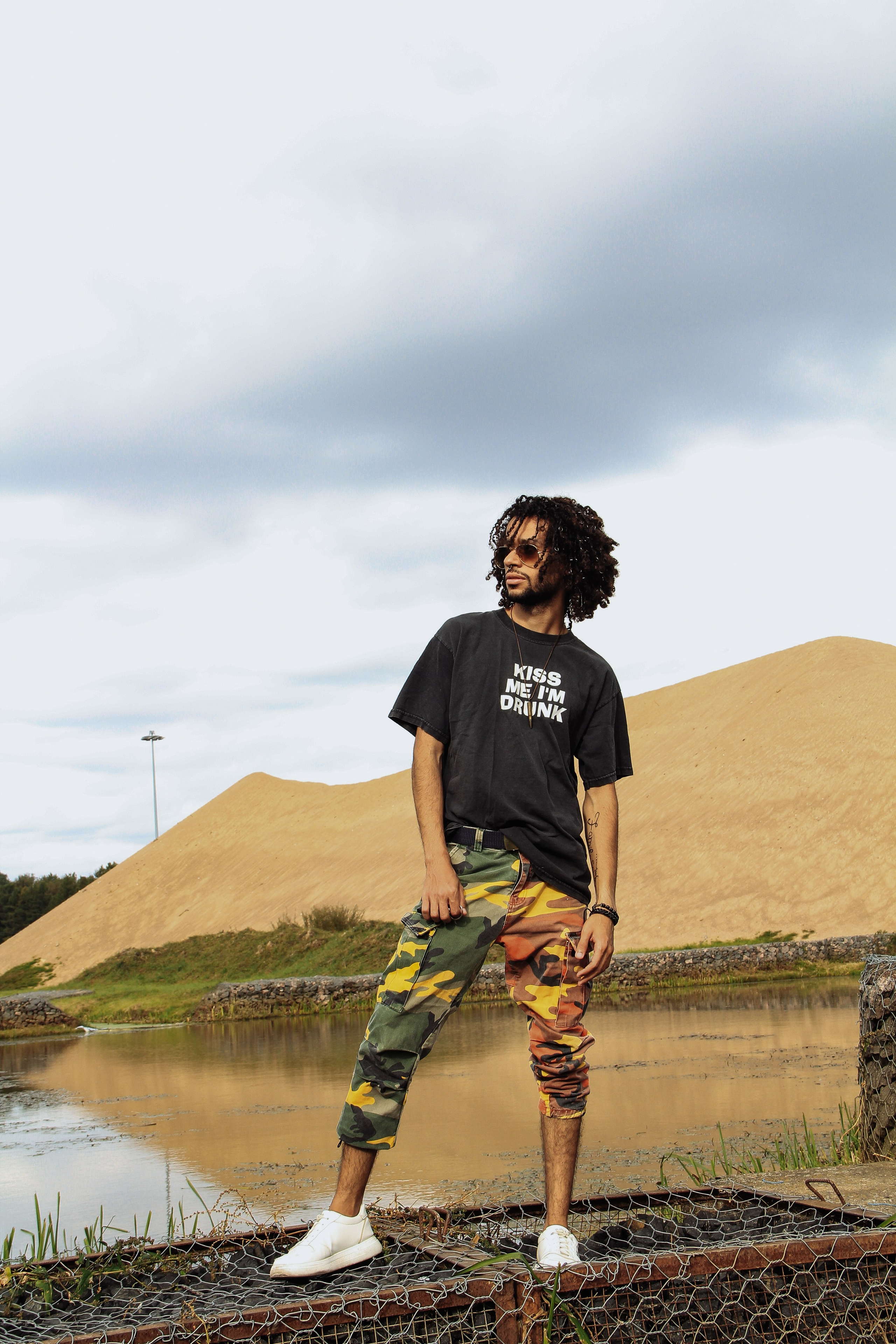 Темнокожий парень в камуфляжных бриджах и белых кедах