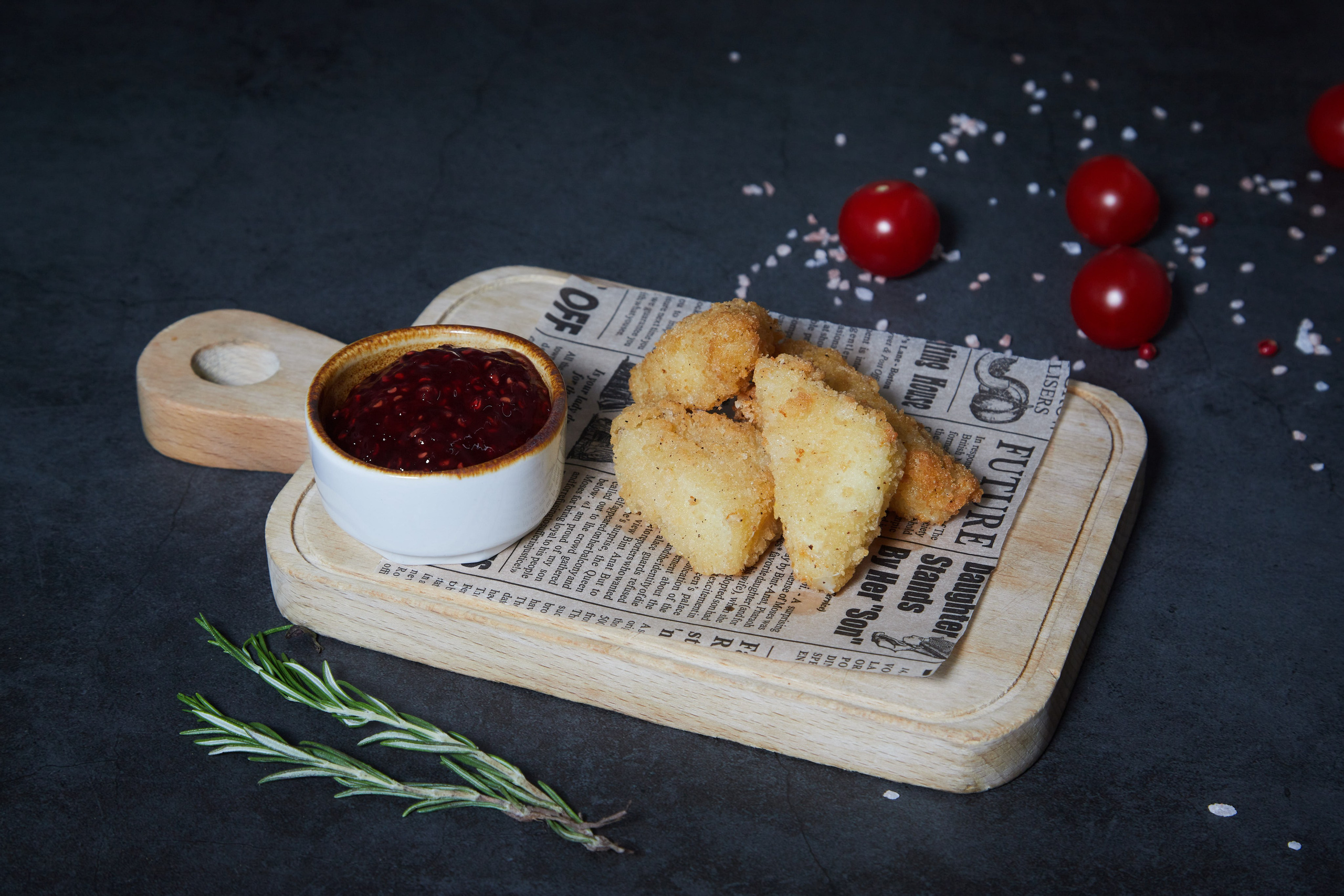 Жареные сырные палочки с соусом на деревянной доске.