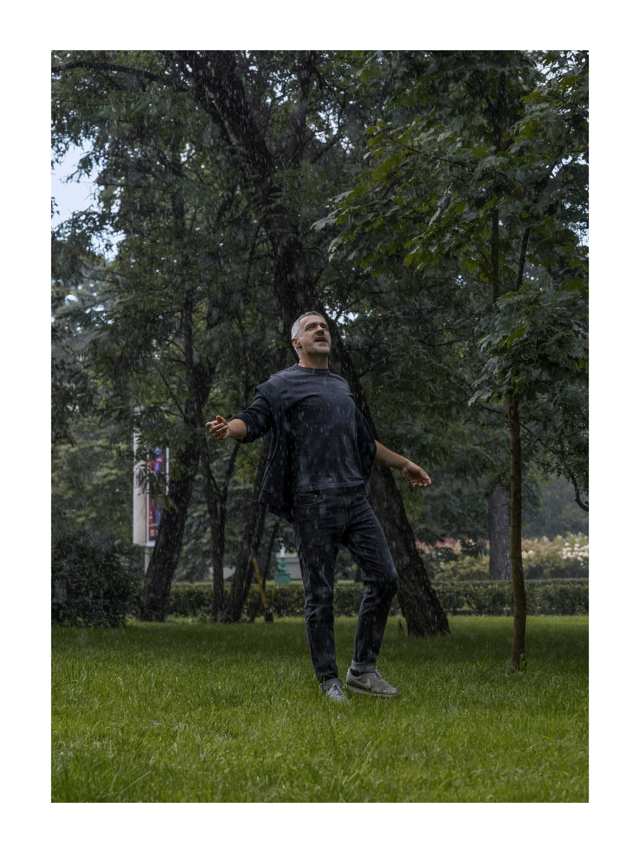 мужчина под дождем, раскинув руки