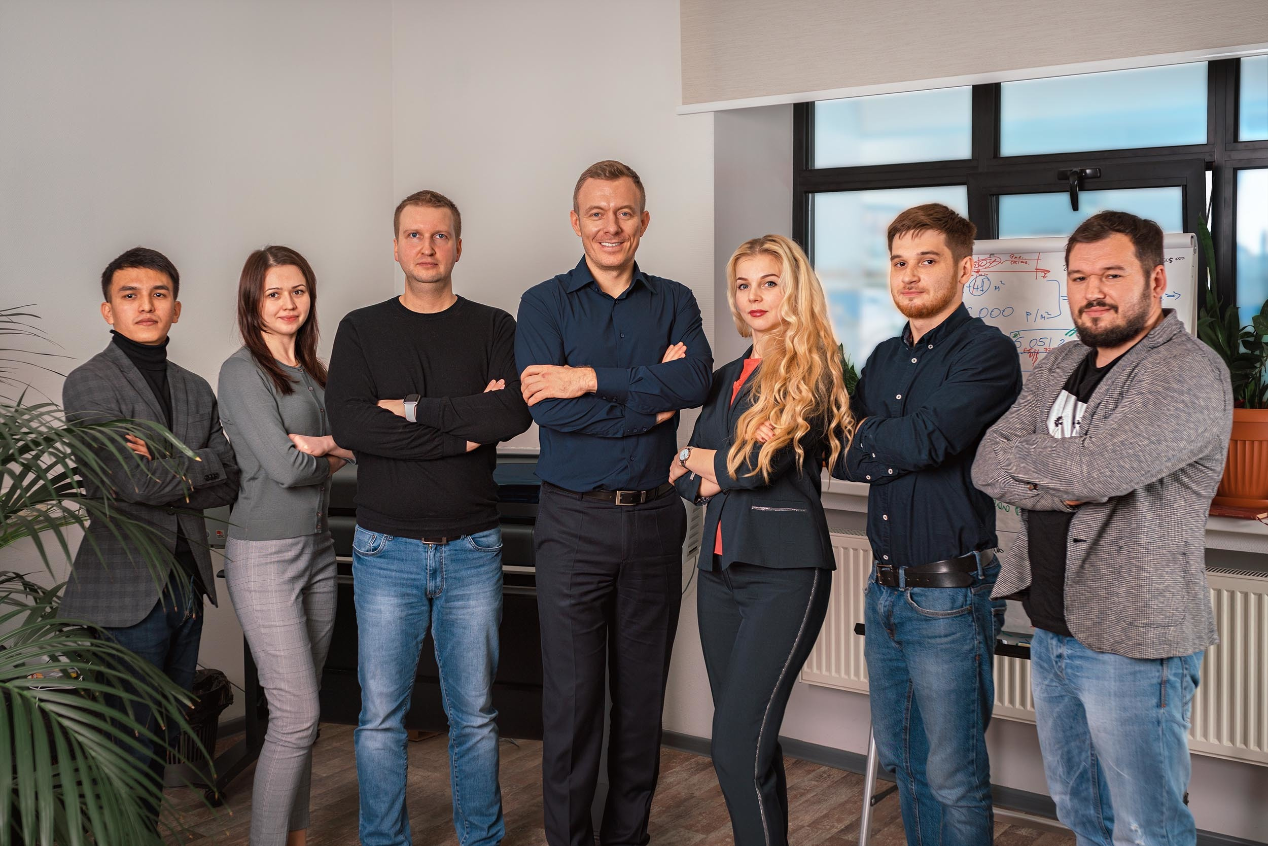 Сотрудники компании смотрят в камеру стоя в офисе