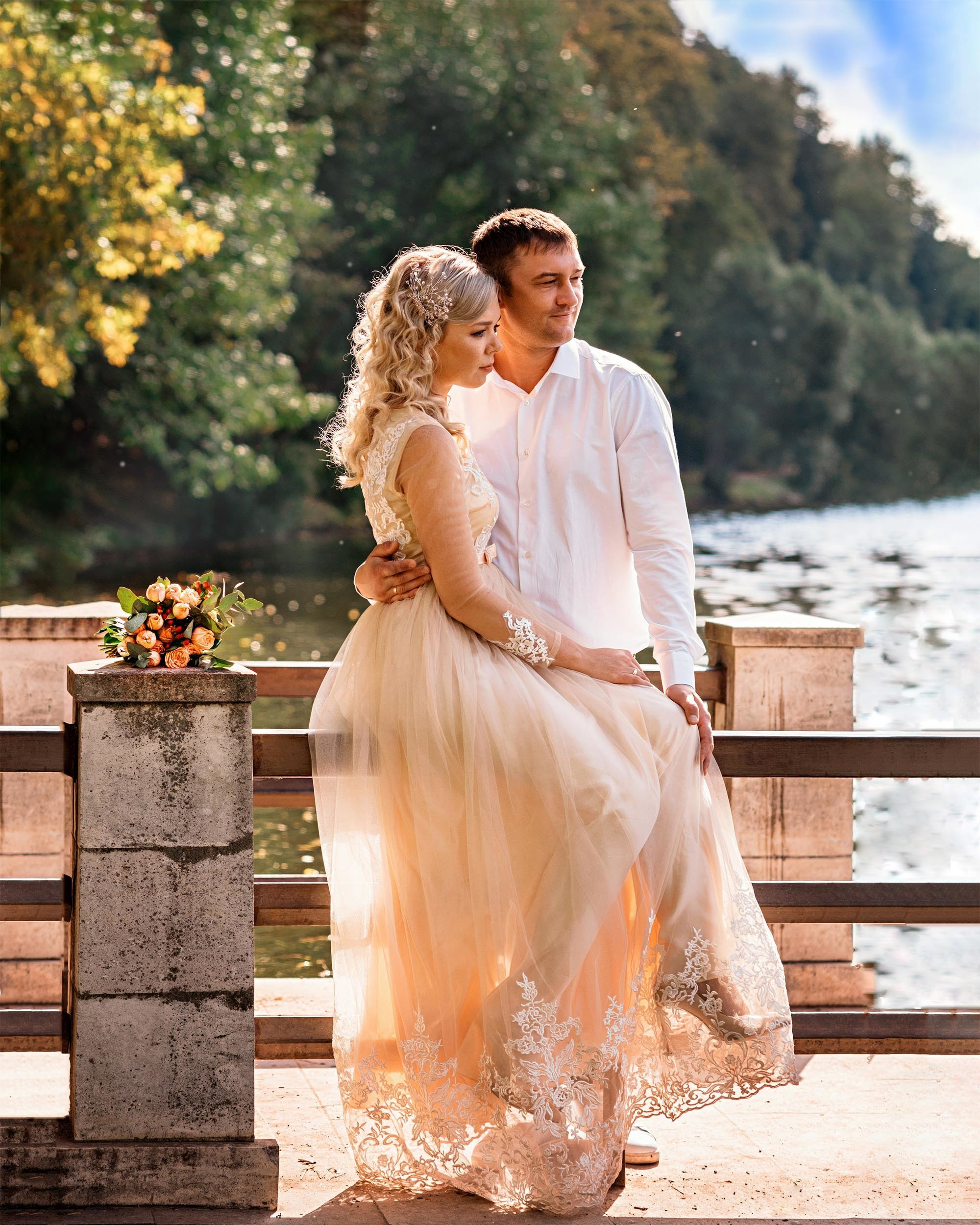 Неаеста сидит на перилах моста на берегу, жених стоит сзади