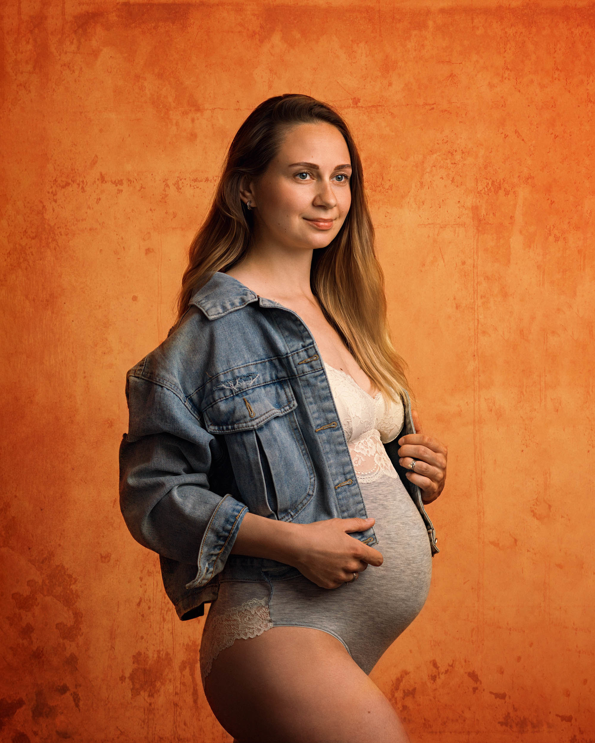 Беременная девушка в длинными волосами в нижнем белье и джинсовке на плечах