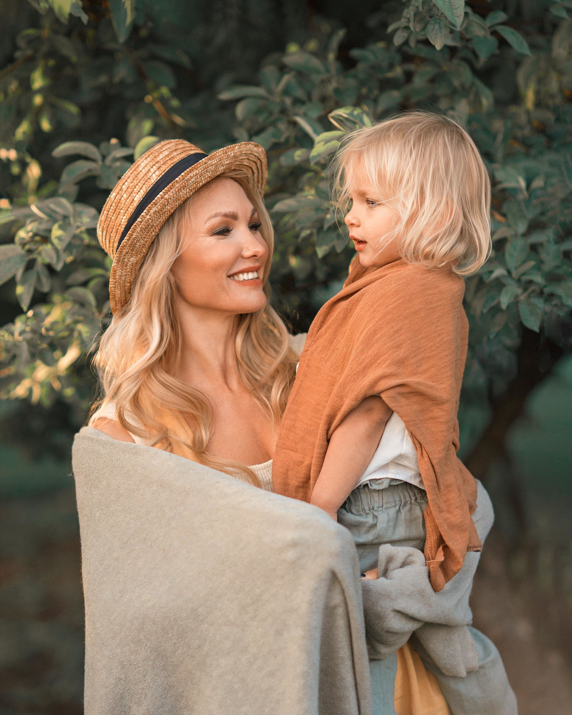 Крупный портрет мамы с ребенком на руках на фоне дерева