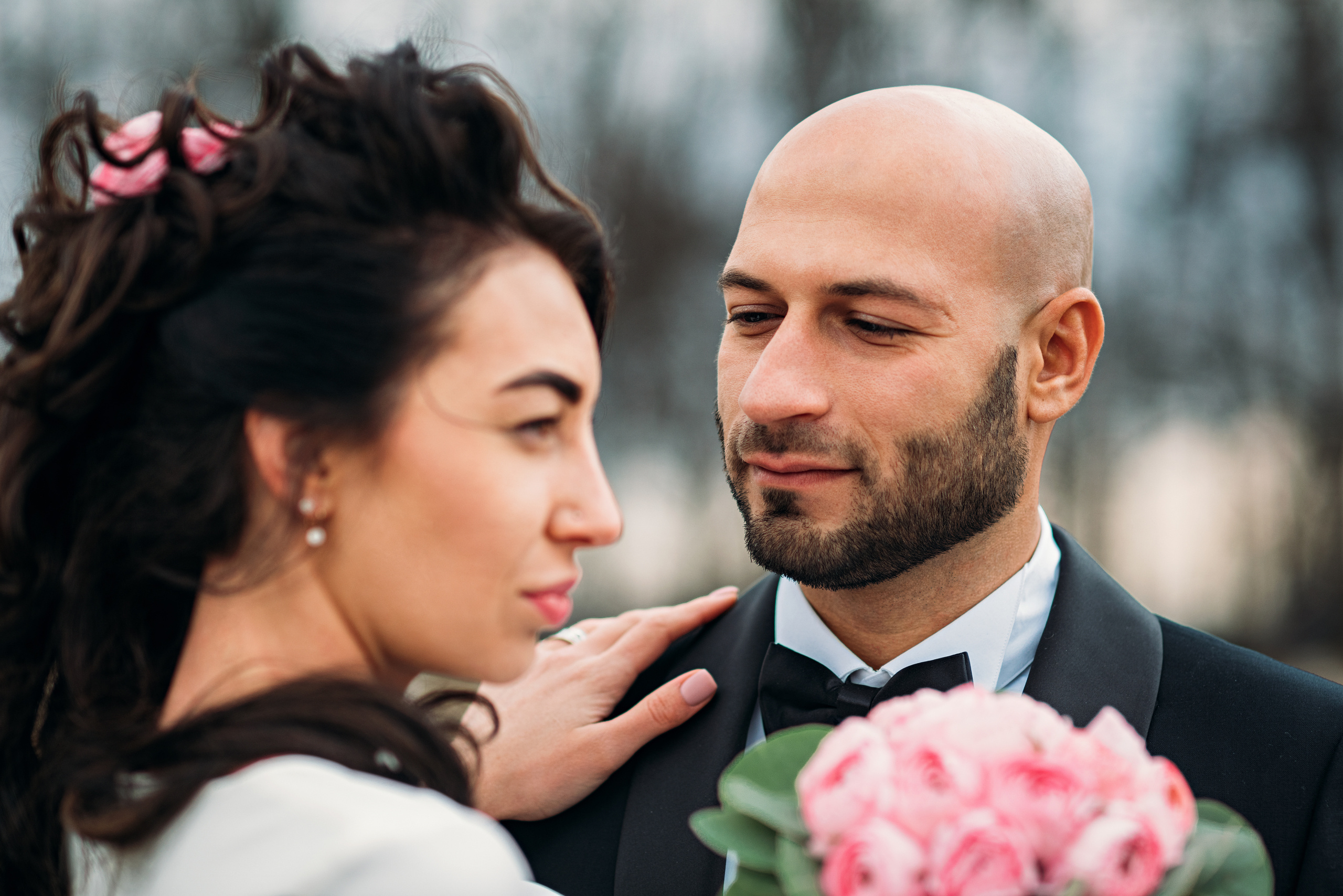 Жених смотрит на невесту, невеста смотрит мимо него, на переднем плане букет