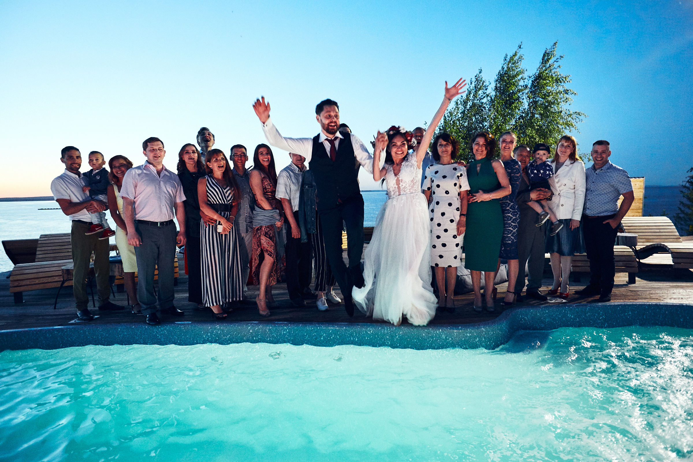 Жених и невеста прыгают в бассеин на свадьбе