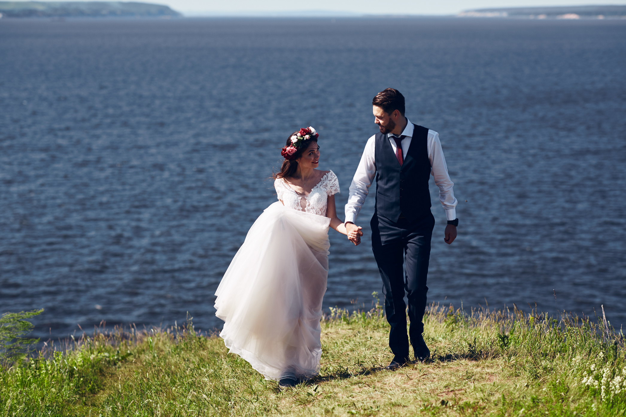 Жених и невеста позируют в красивой локации с деревом и морем