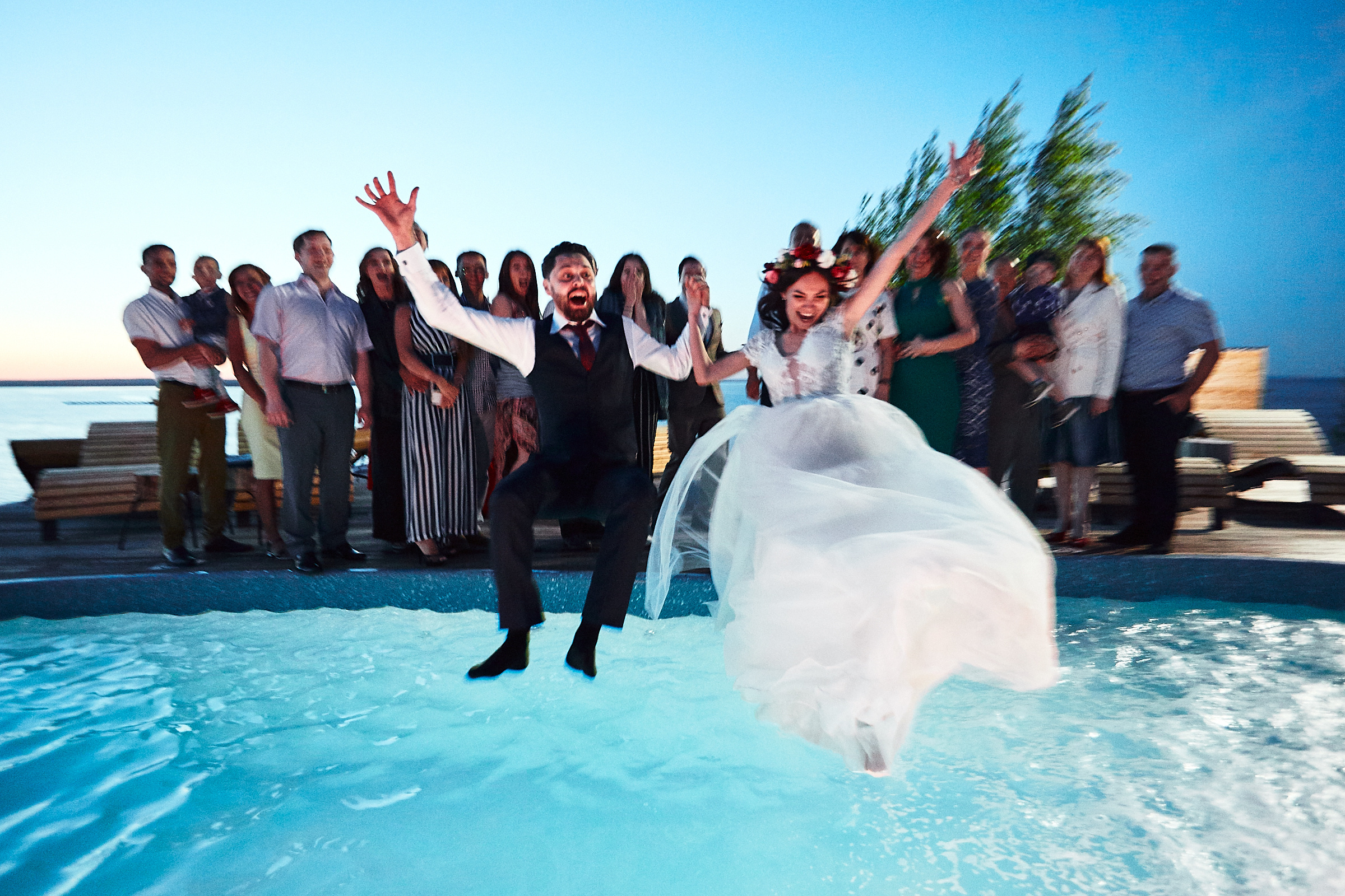Жених и невеста прыгают в бассеин на свадьбе