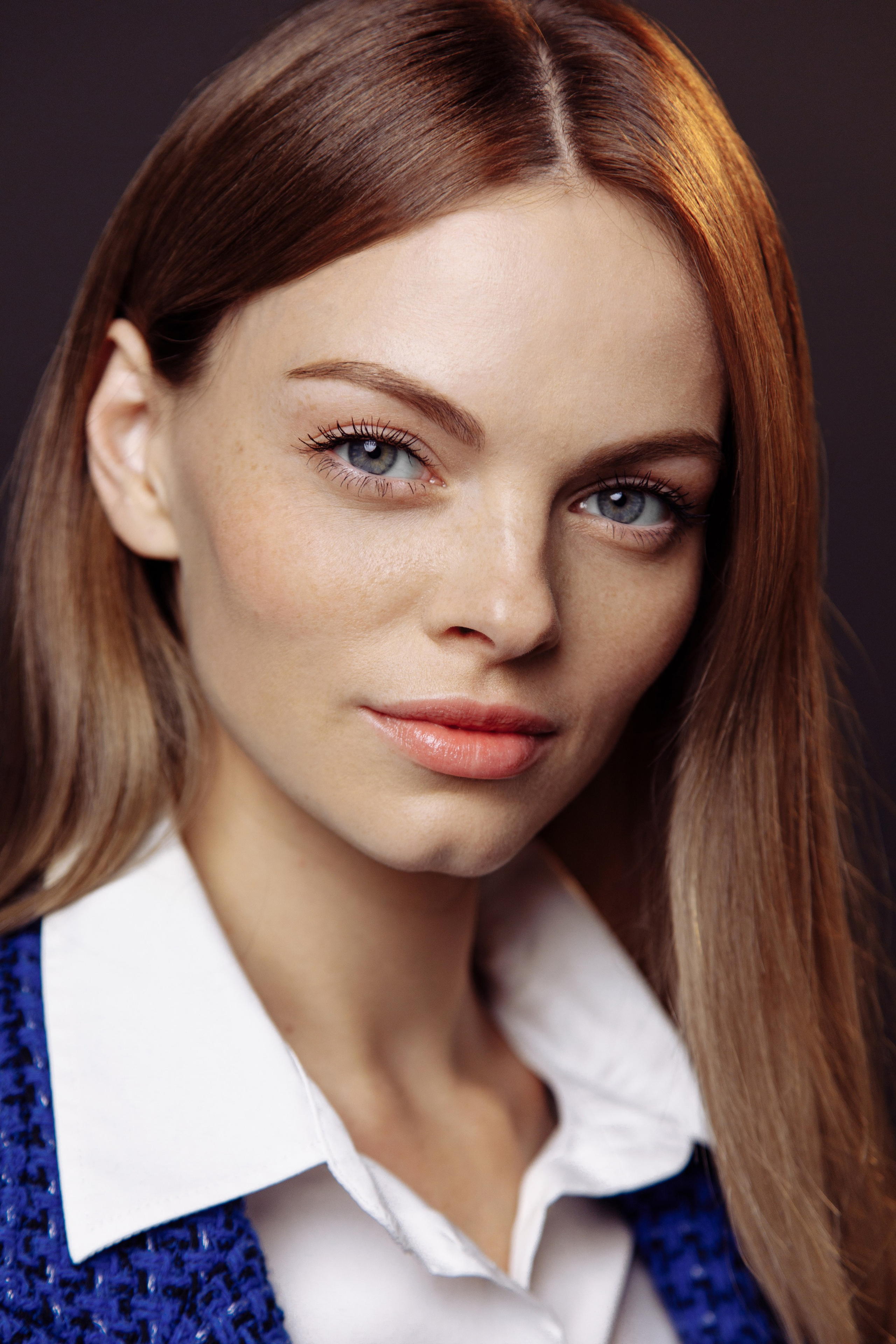 Крупный план девушки в строгом деловом костюме и с серьёзным выражением лица.