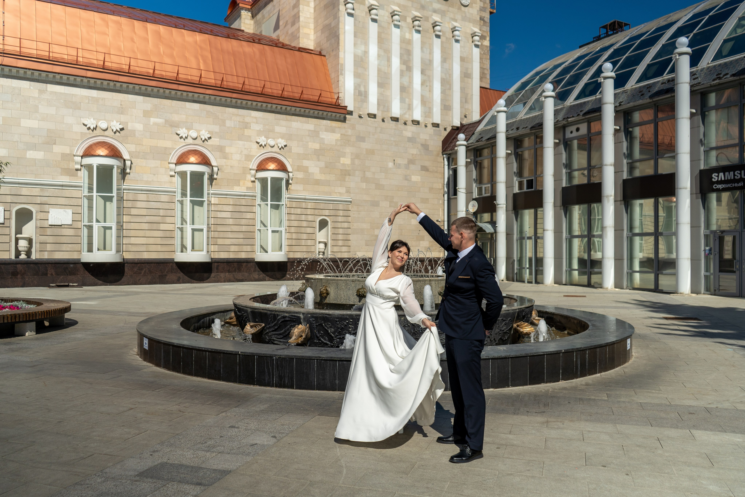 Жених кружит в танце невесту в белом длинном платье у театра кукол в Воронеже