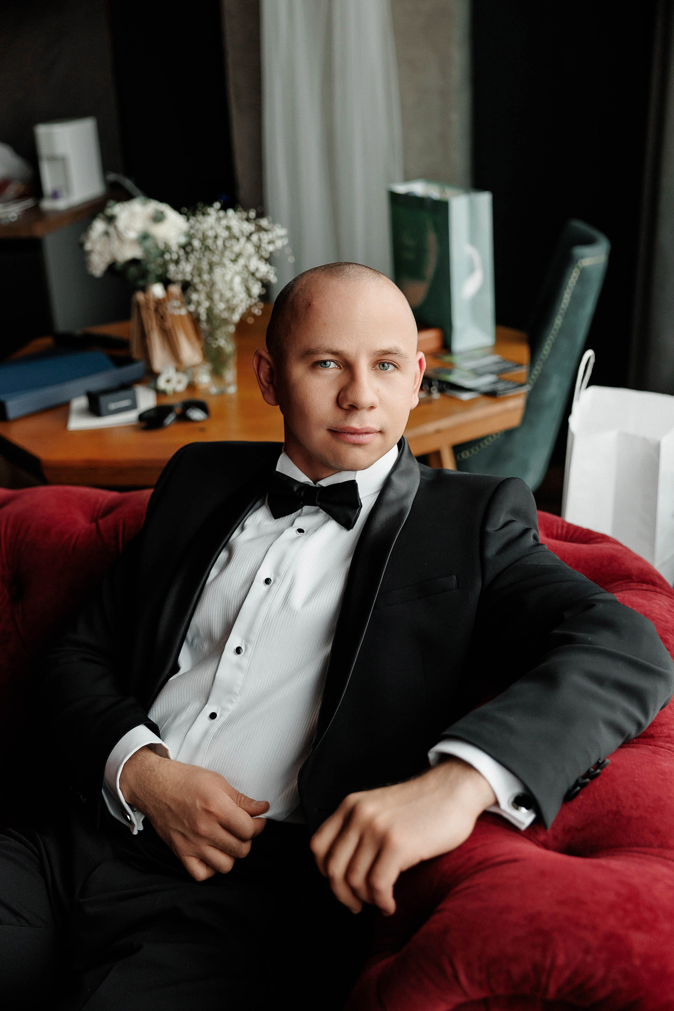Потрет жениха на красном диване в интерьере. Фотограф Денис Перминов
