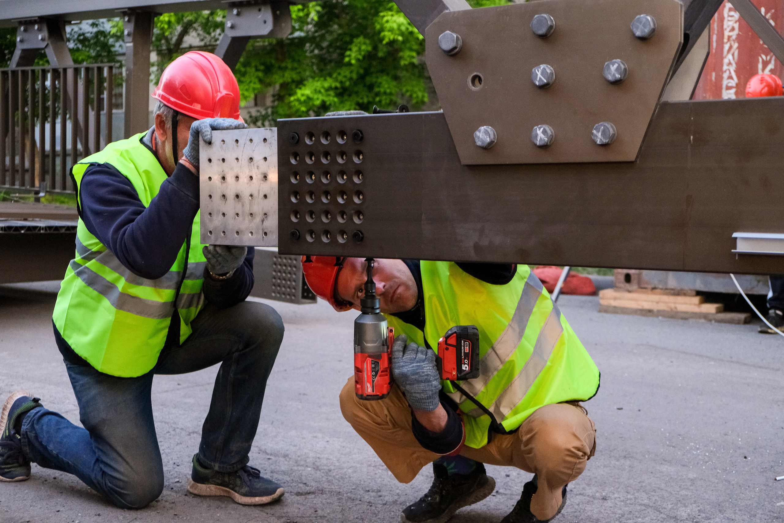 Фотография рабочих помогающих руками установить ровно мост 