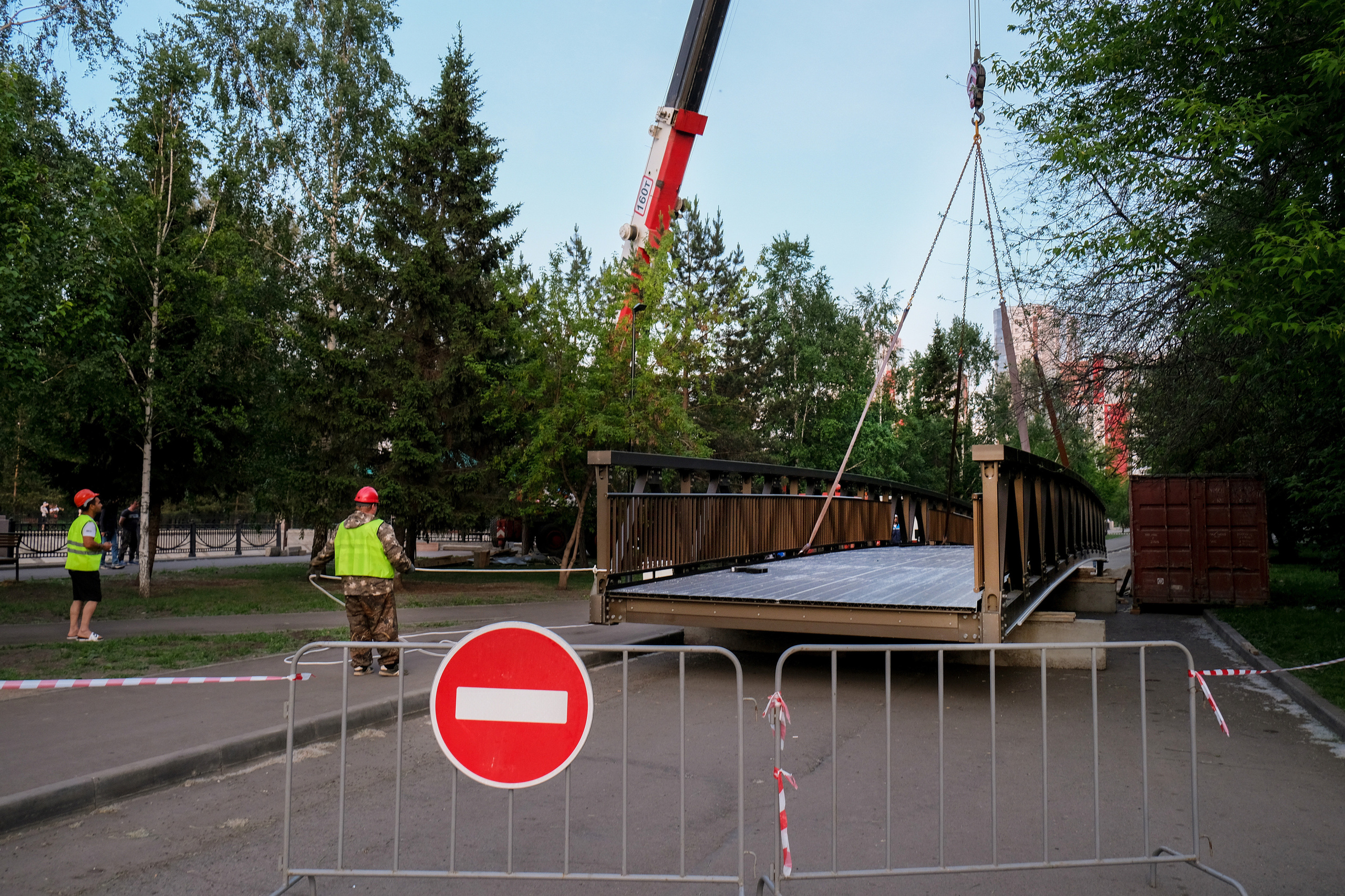 Фотография рабочих готовящих подъем металлической конструкции моста 