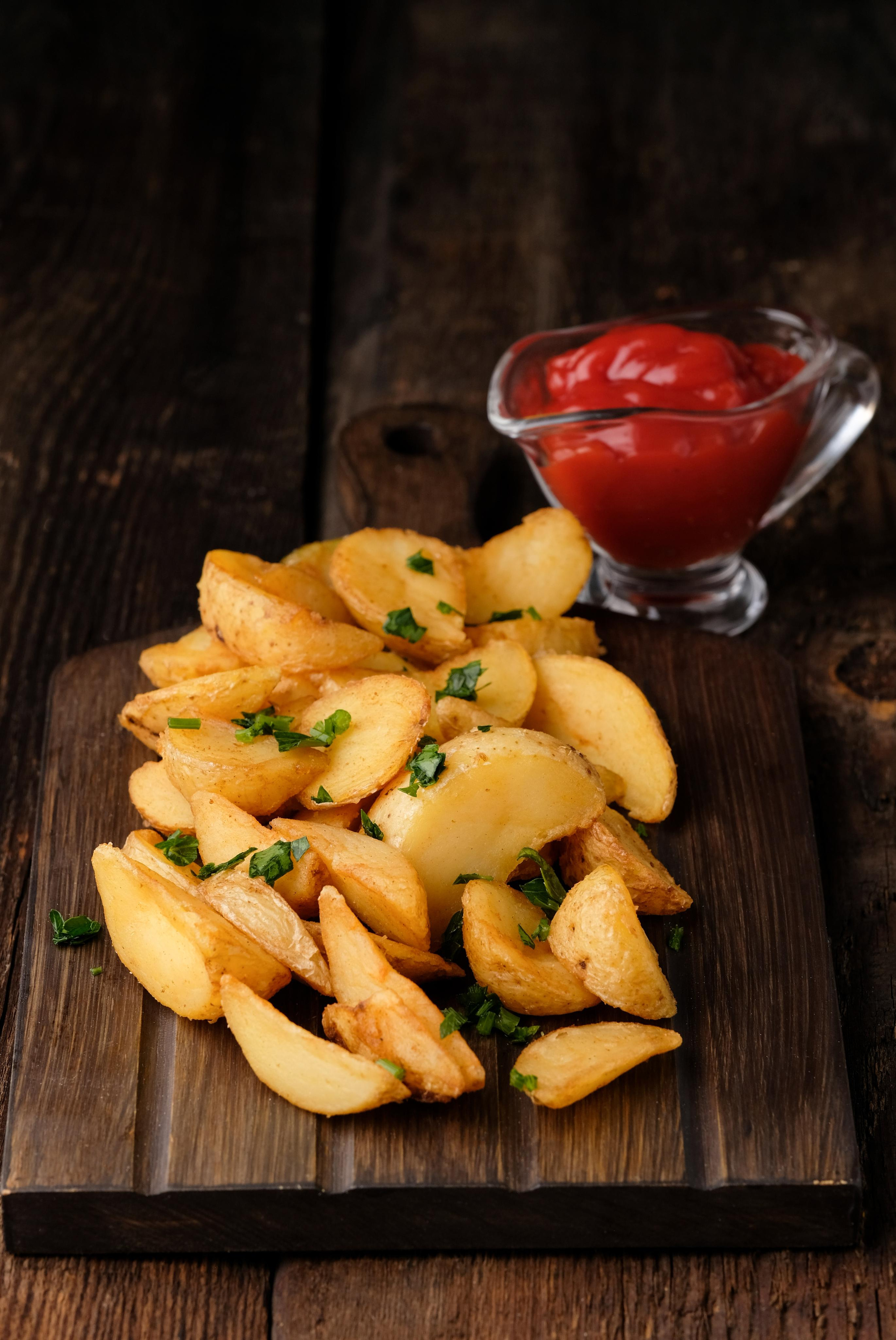 Картошка фри с томатным соусом на деревянном фоне 