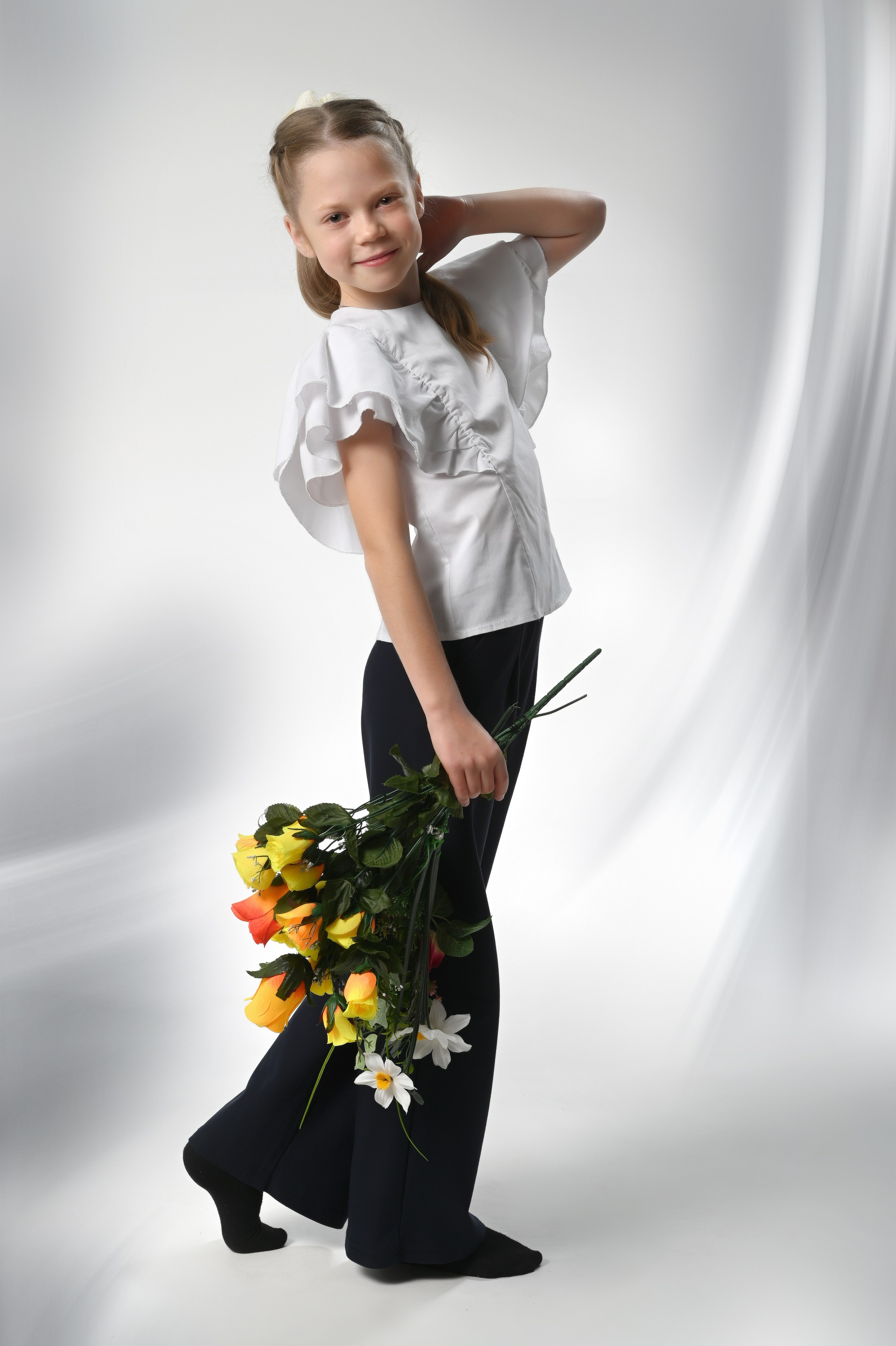 Девочка в выпускном костюме держит букет в фотостудии