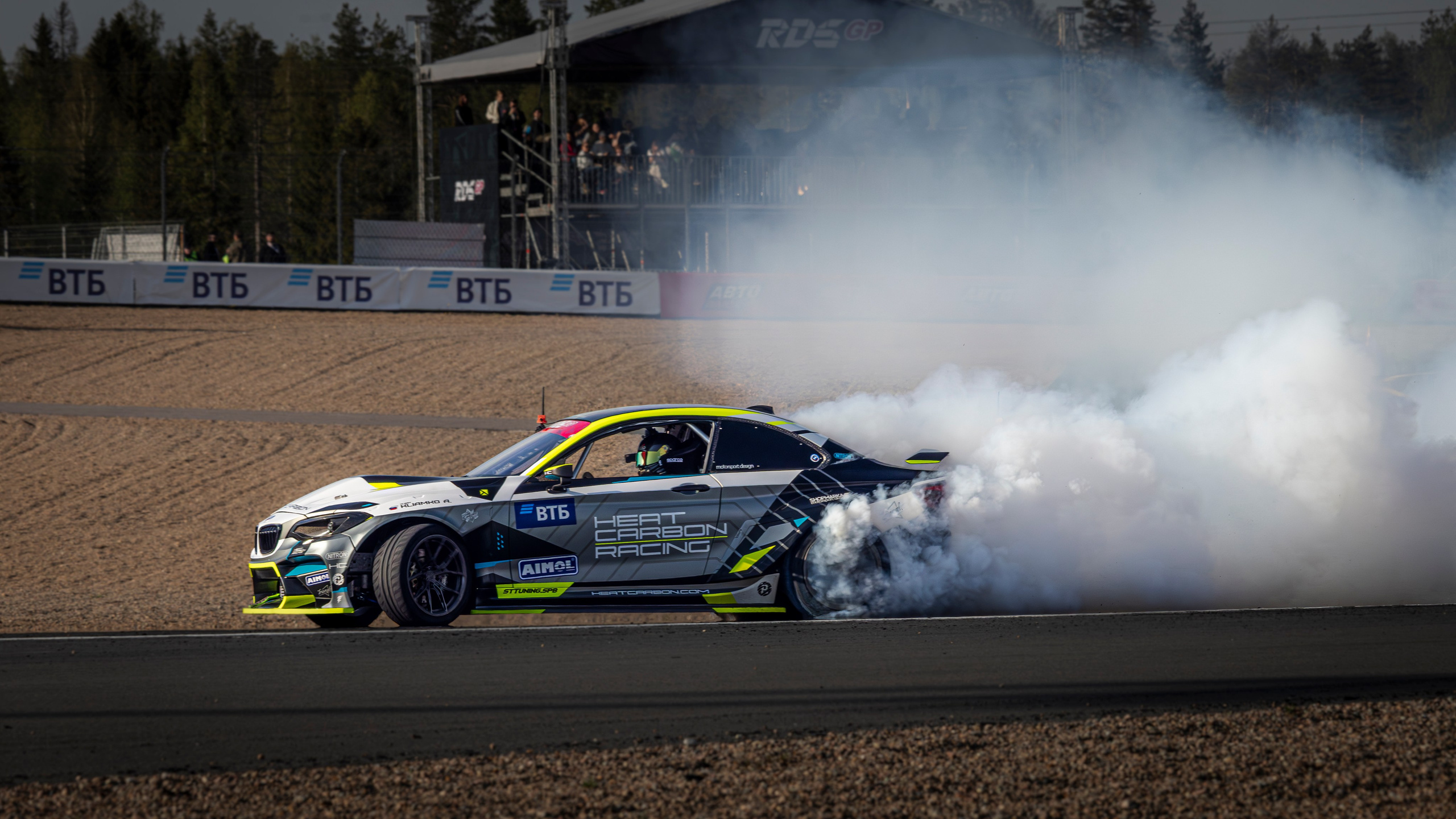 Автомобиль резко входит в поворот, оставляя след от шин на асфальте.