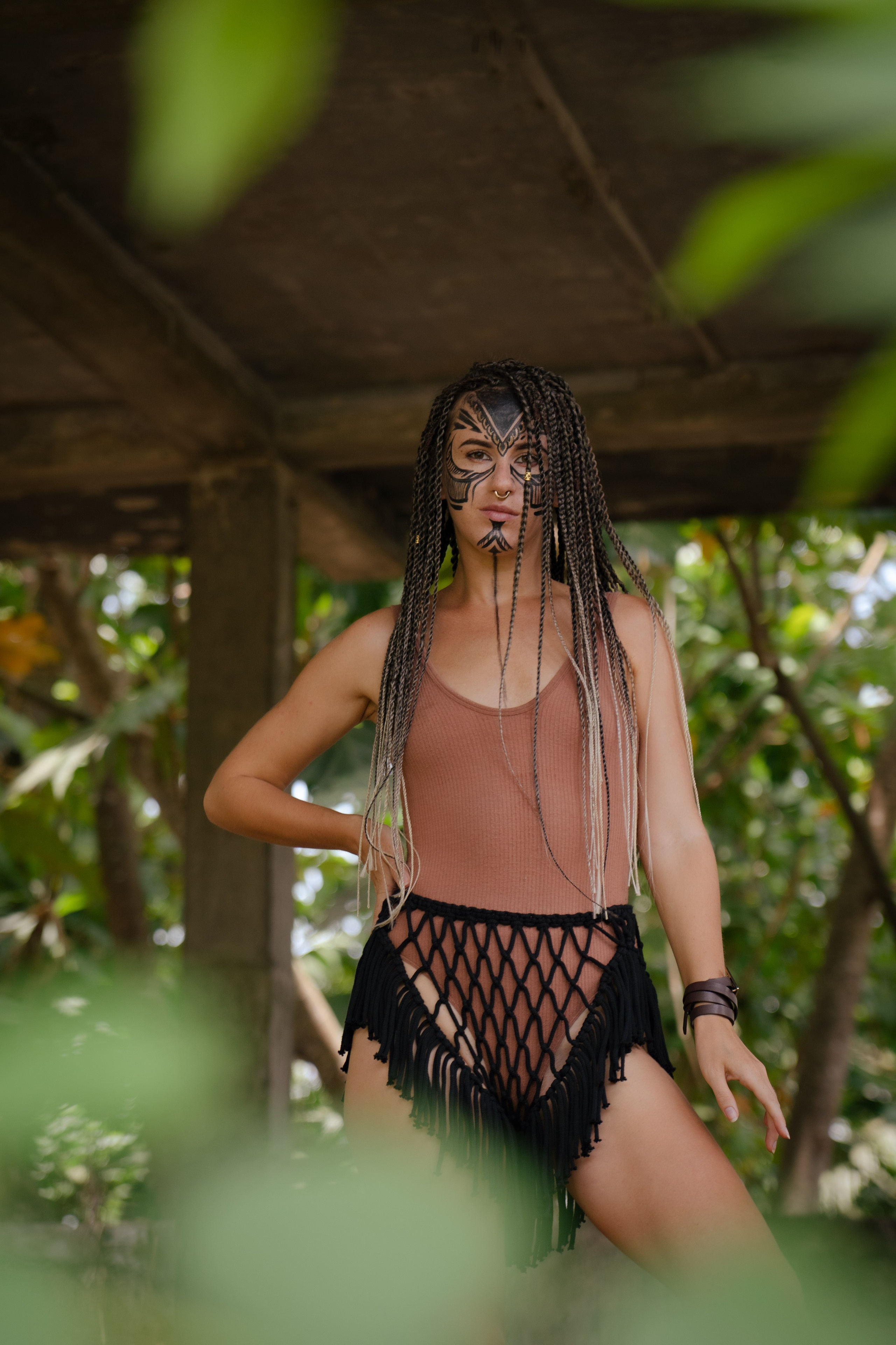 a girl with braids and face paint among vines and trees