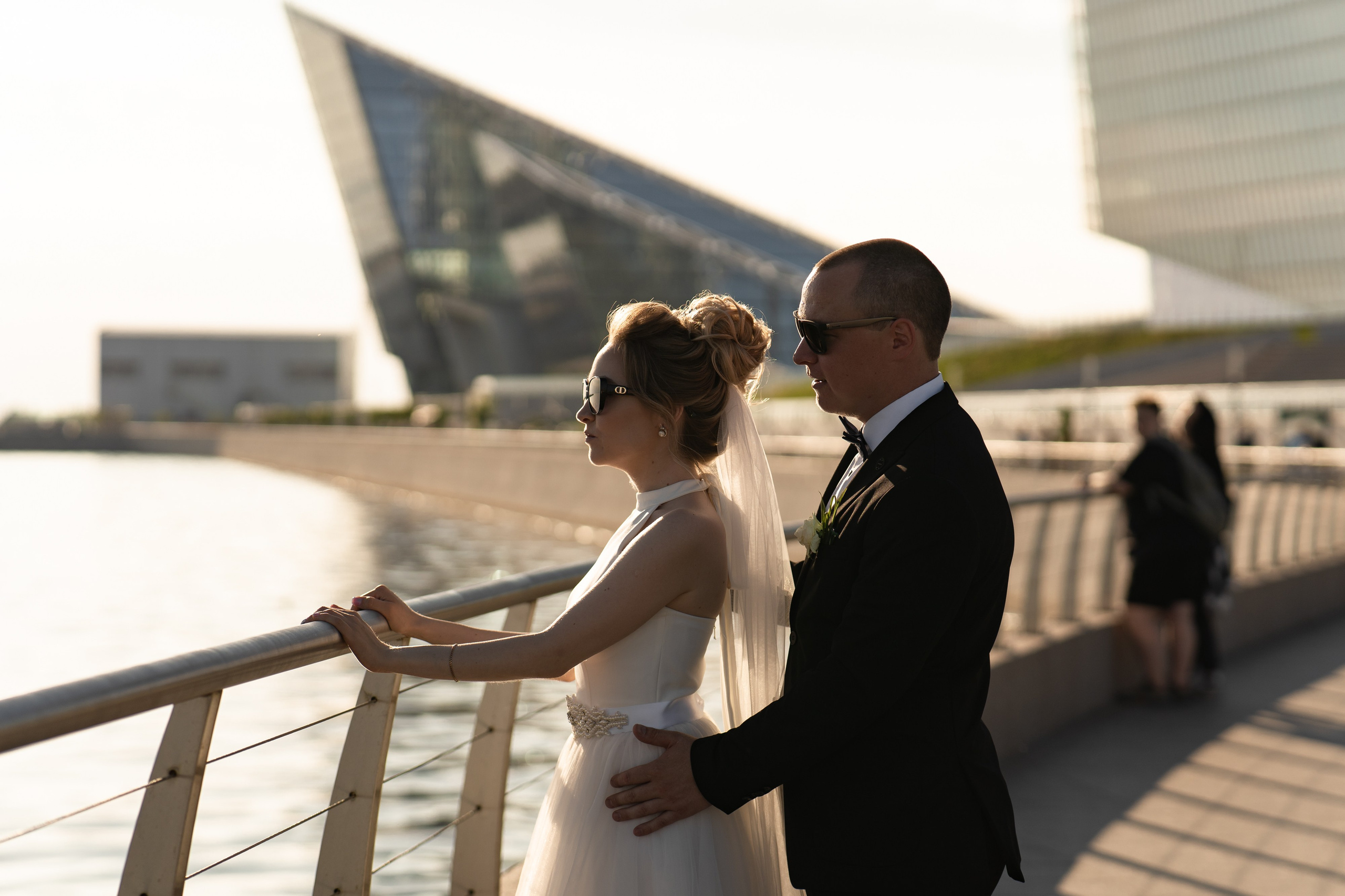 Жених стоит рядом с невестой на смотровой площадке на набережной в Лахта центре на закате
