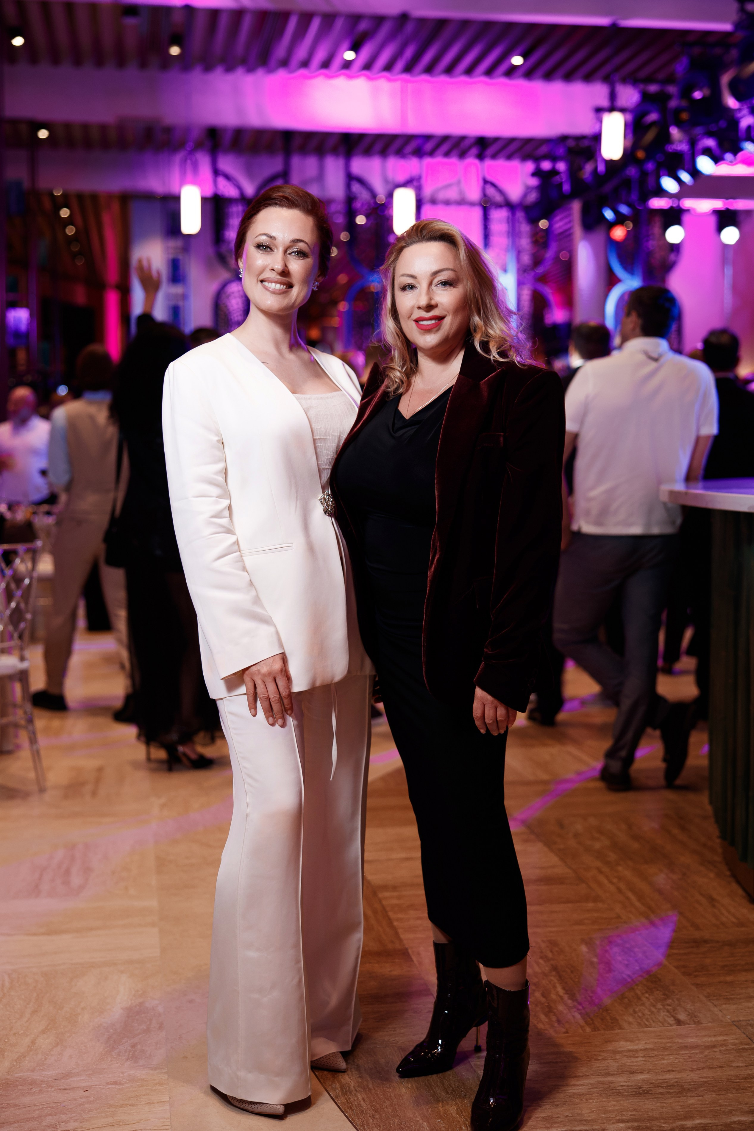 Ведущие: Две гостьи в элегантных белом и черном нарядах позируют в зале отеля.