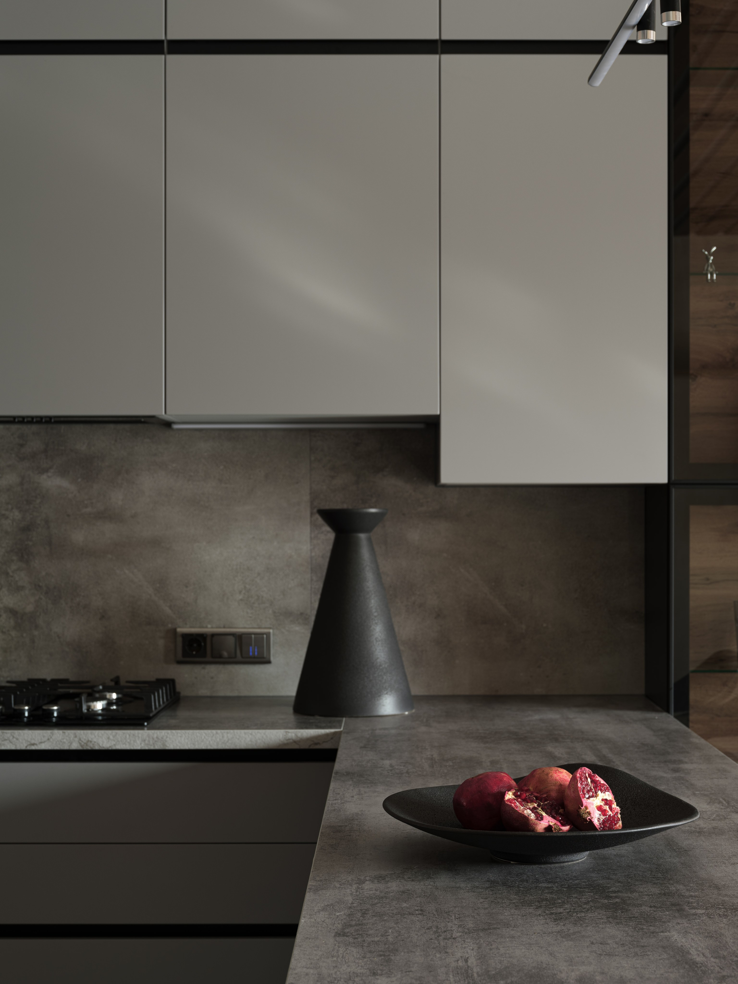 Фрагмент современной кухни в серых тонах с бетонной фактурой и минималистичной посудой. Стильный акцент — гранат в керамической тарелке. Атмосферу создала дизайнер Алина Дёрова, стилист Наталья Якушева, фото Сергей Денисенко.
