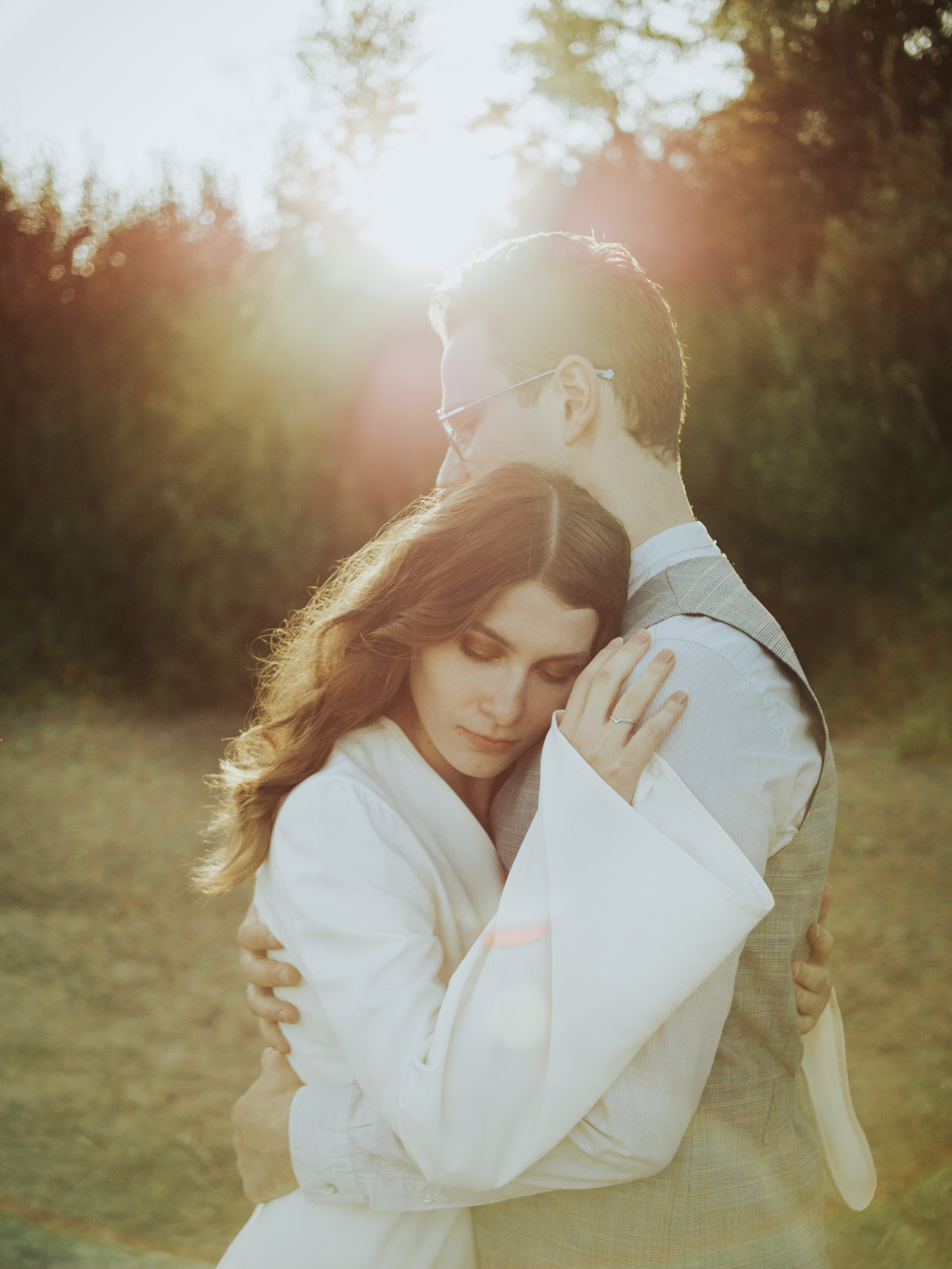 Пара нежно обнимается на тихой лесной поляне, окруженная теплым золотистым светом. Этот момент отражает их глубокую связь и привязанность.