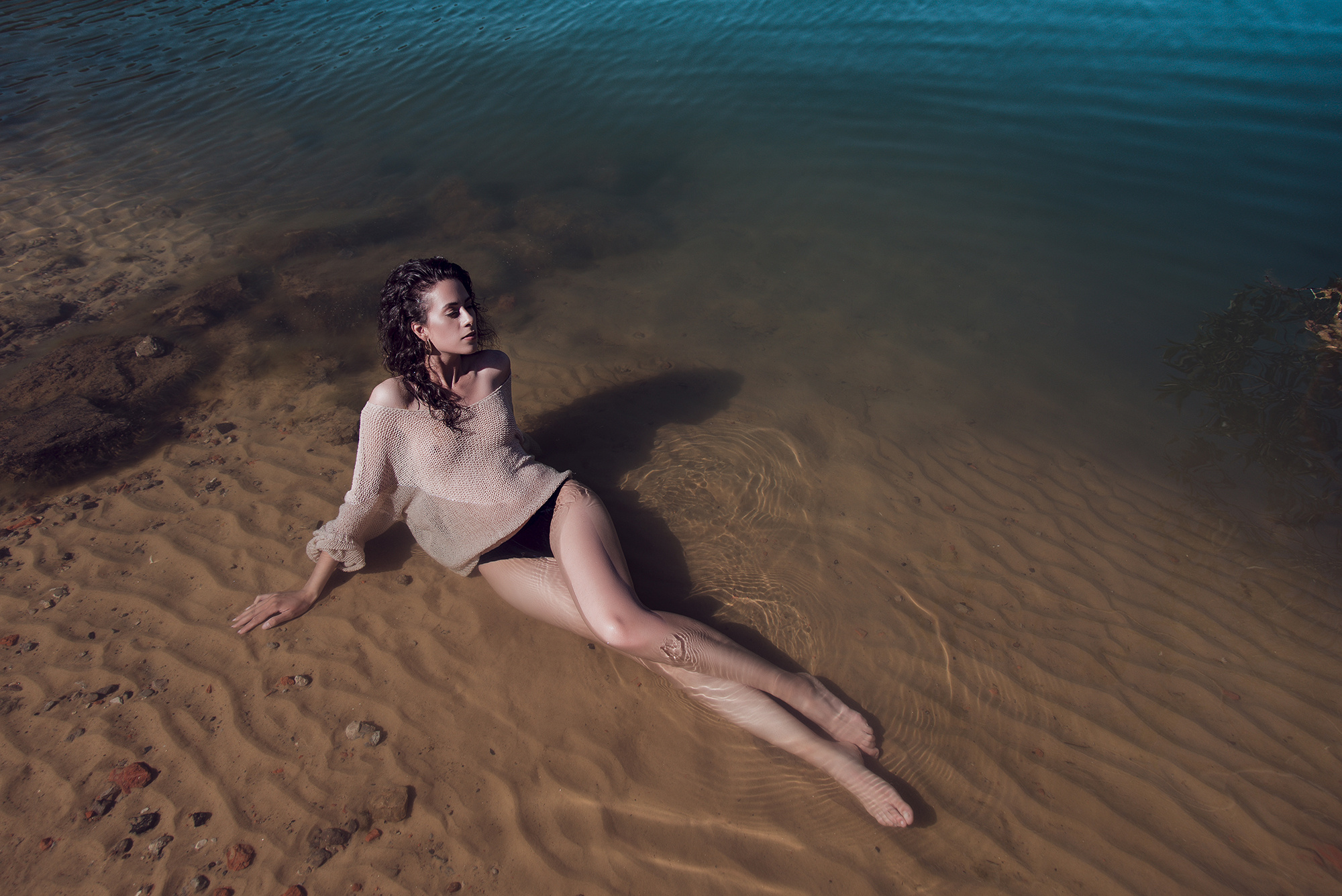 Высокая девушка с длинными ногами лежит в море.