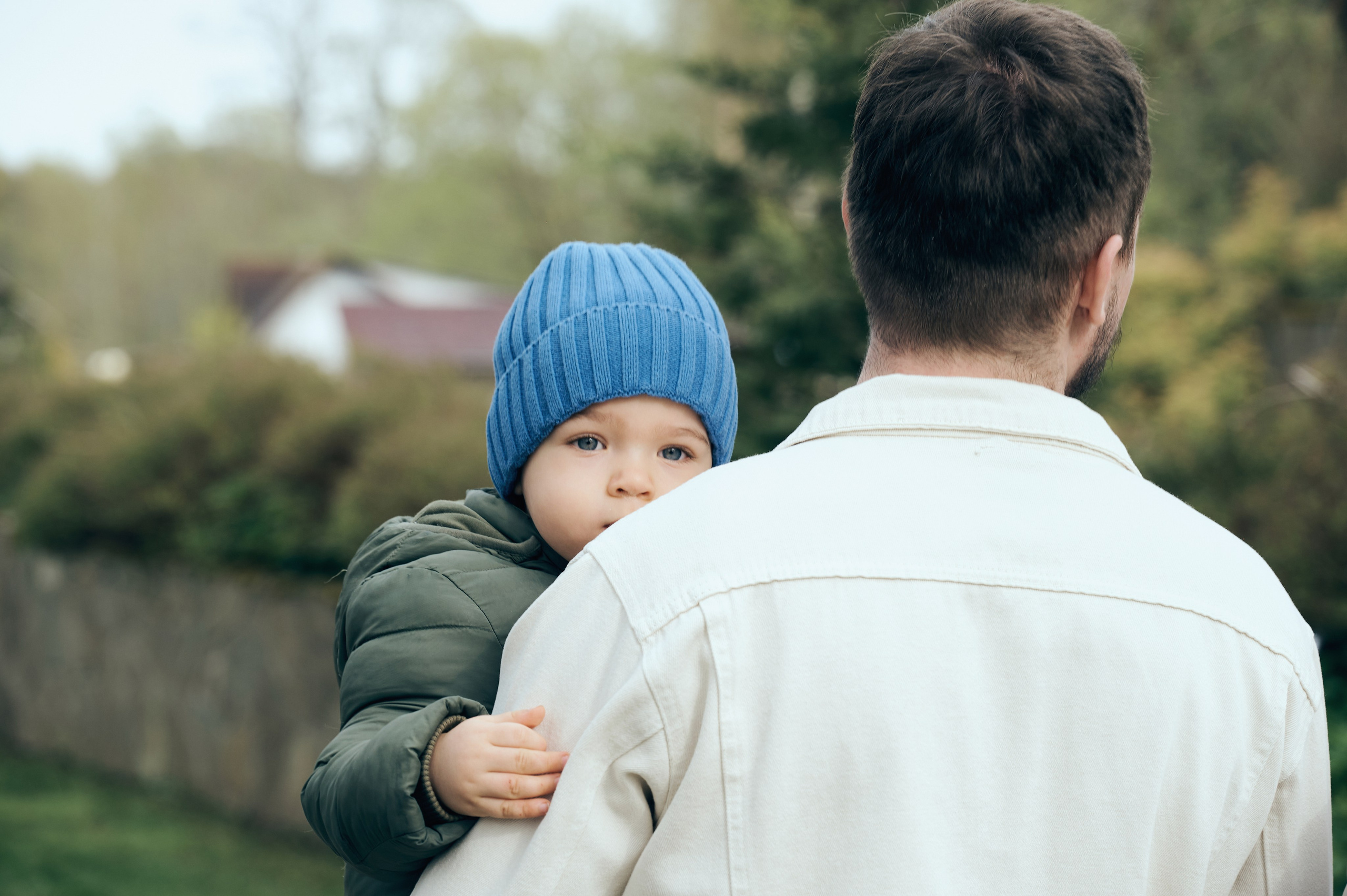 Мальчик в синей шапке обнимает мужчину за плечи и смотрит в камеру