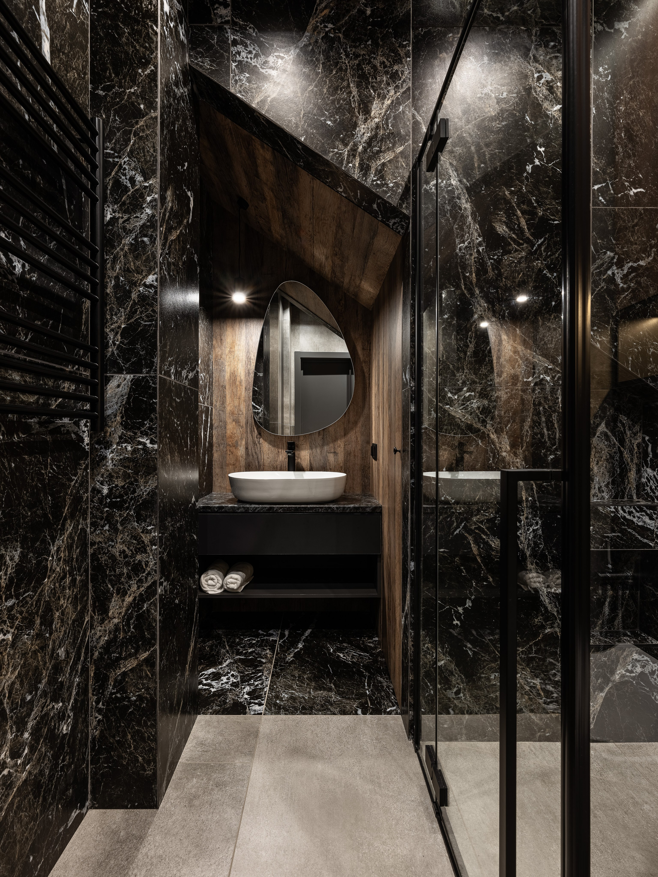 Ванная комната с оригинальным ракурсом на подвесную тумбу с раковиной, деревянную отделку и душевую зону с черным мрамором и стеклянной перегородкой; дизайн Екатерина Мищенко, фото Сергей Денисенко.